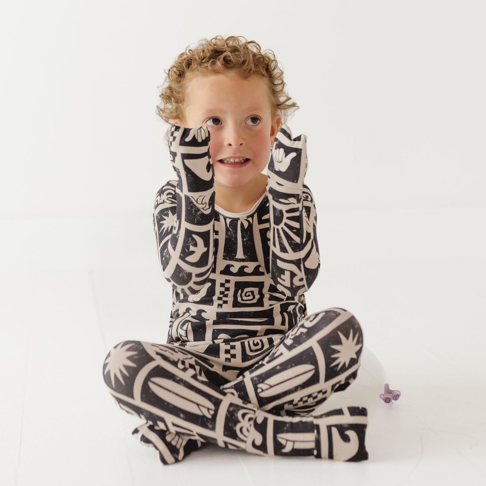Child wearing a black and white patterned outfit sitting on a white background