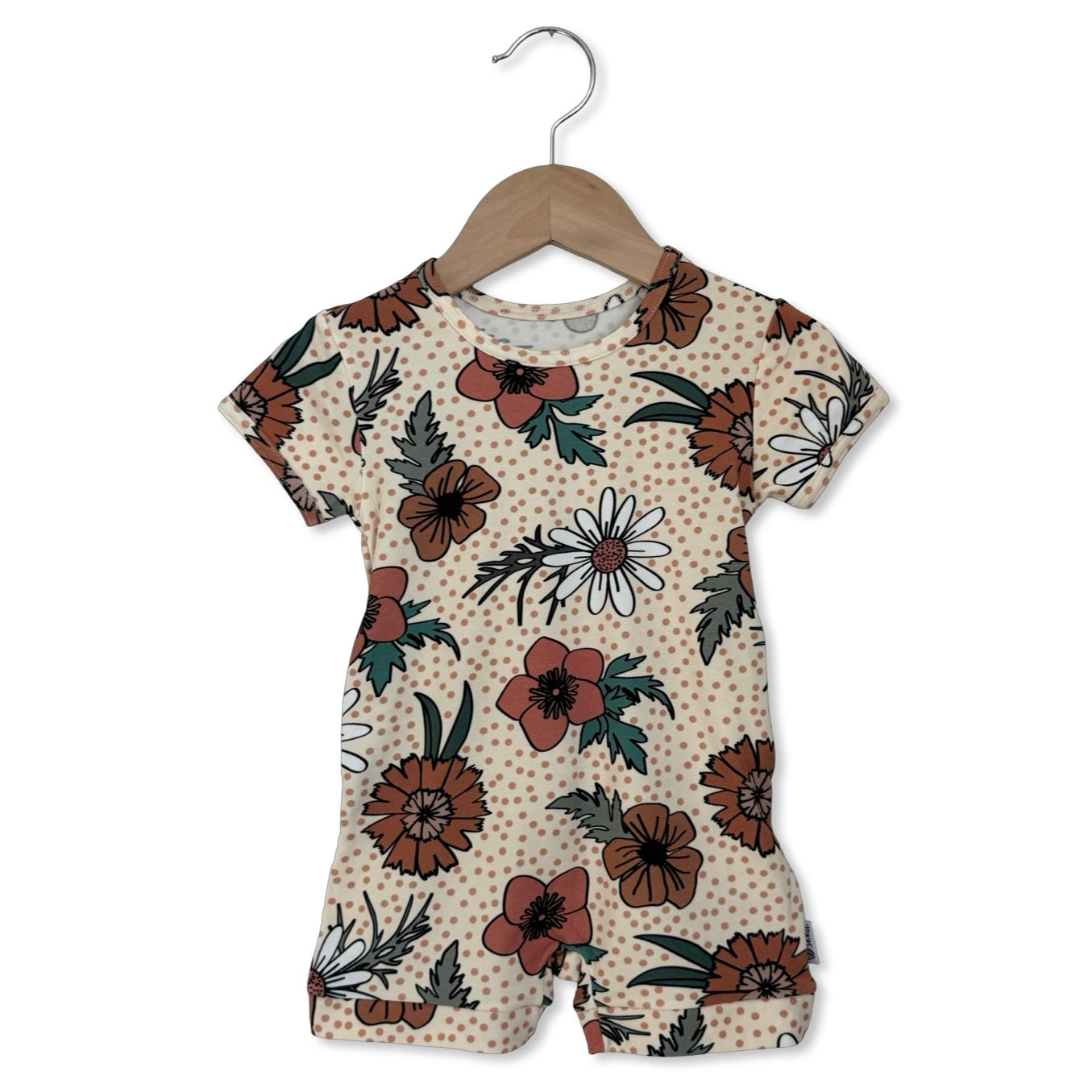 Children's romper with floral pattern on a hanger against a white background