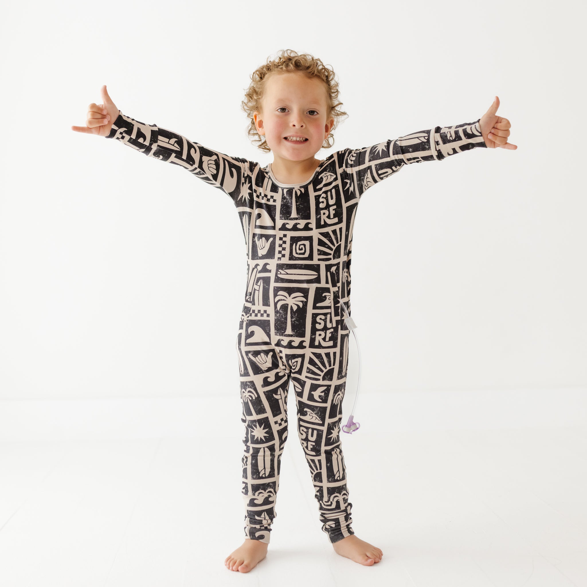 Child wearing a black and white patterned onesie on a white background
