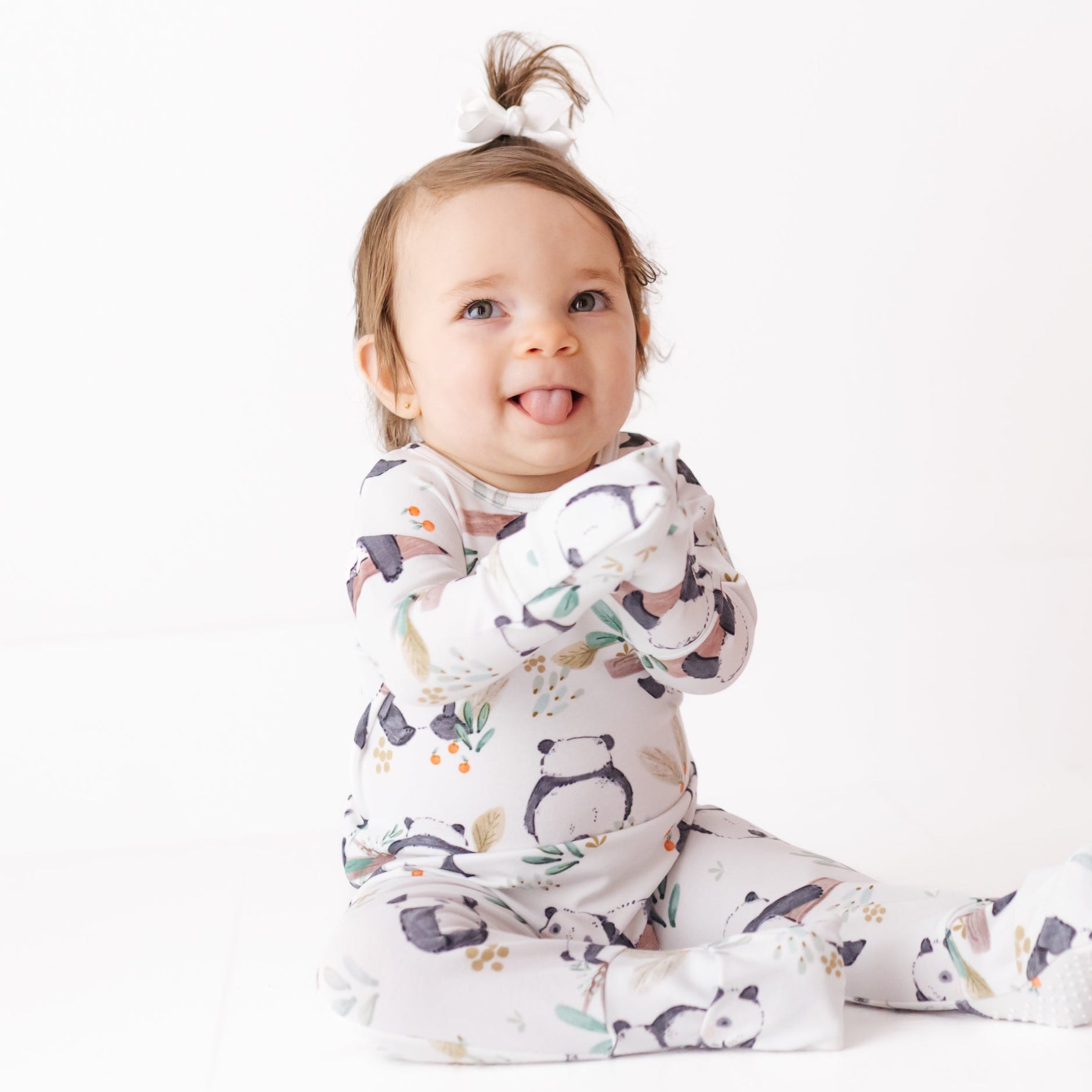 Baby wearing a white onesie with animal prints on a white background