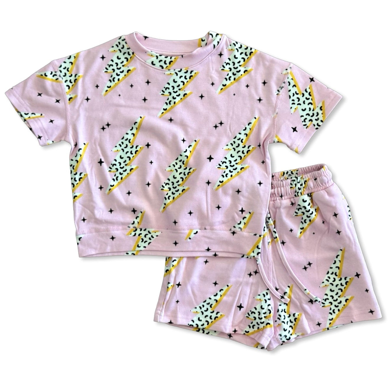 Children's pajama set with pink background and green dinosaur print on a white background