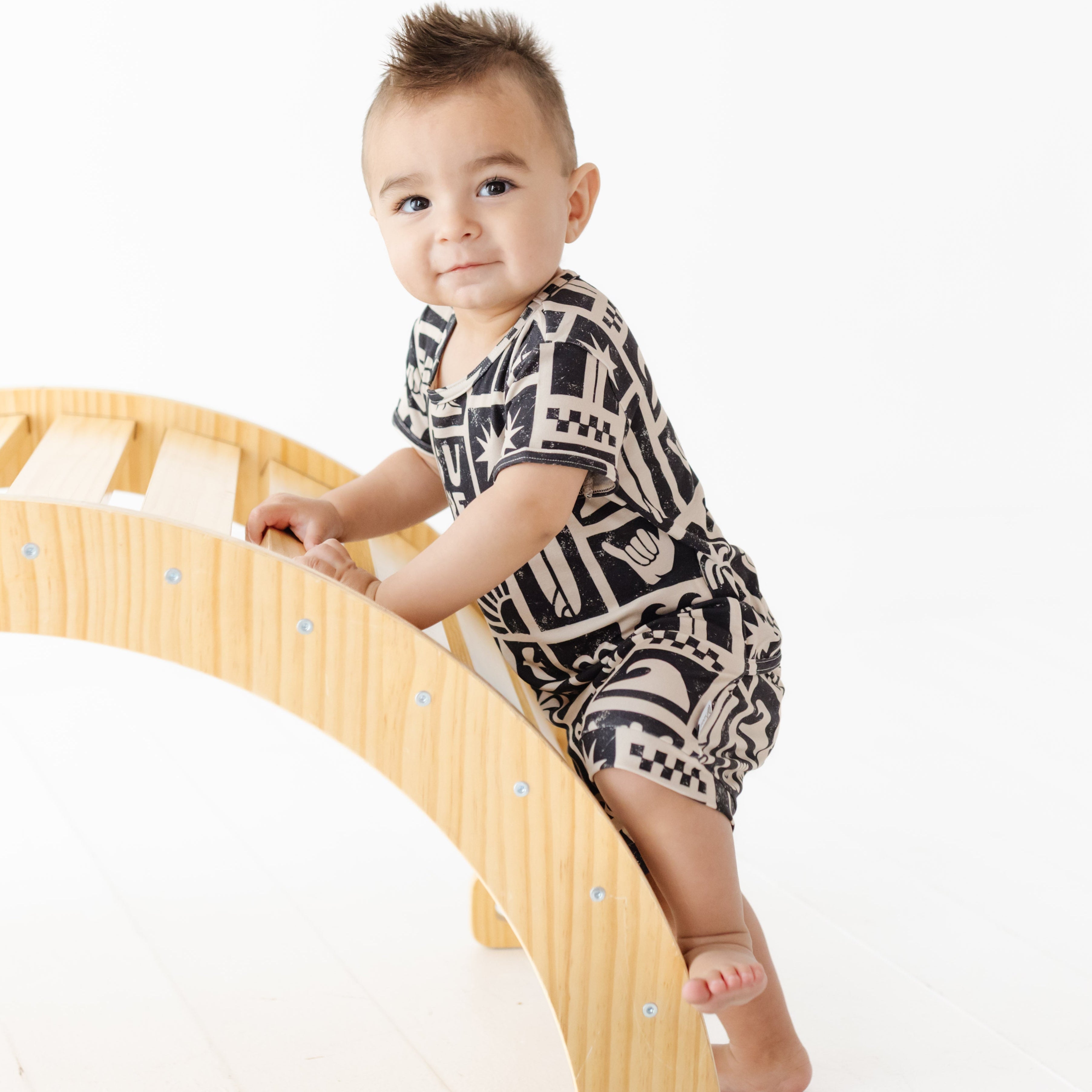 Baby climbing a wooden climbing toy on a white background