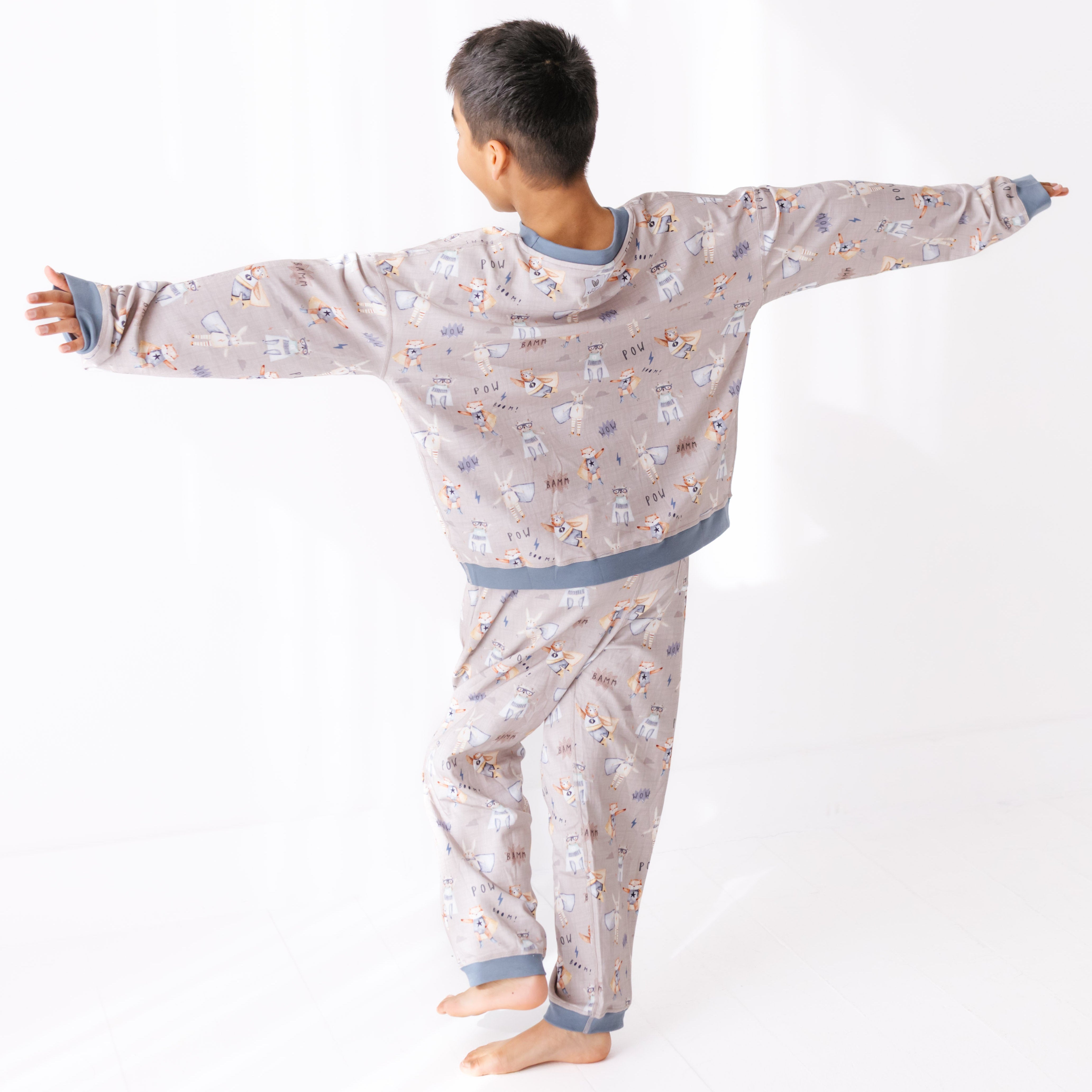 Child wearing a patterned pajama set with arms outstretched on a white background