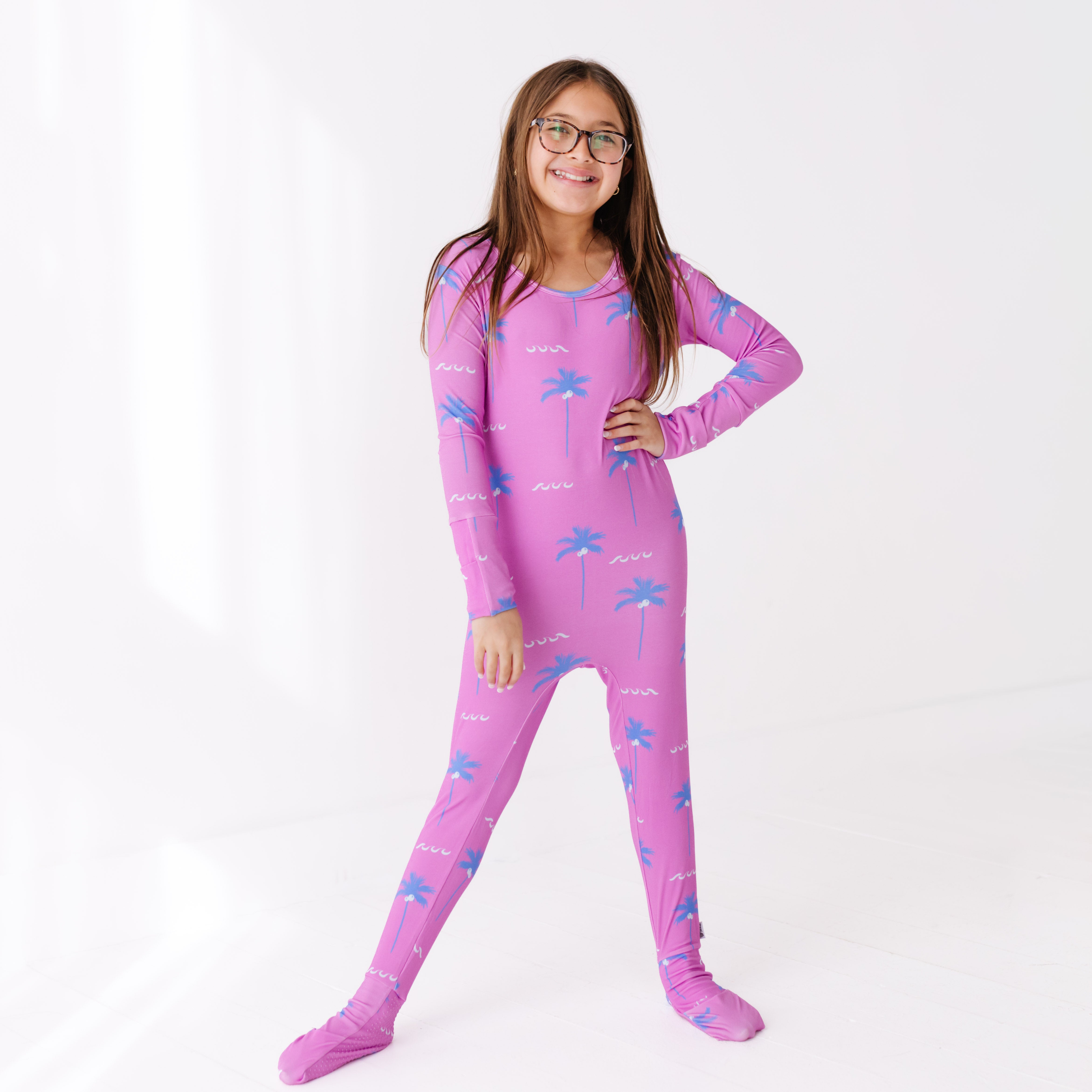 Girl wearing a pink onesie with palm tree design on a white background