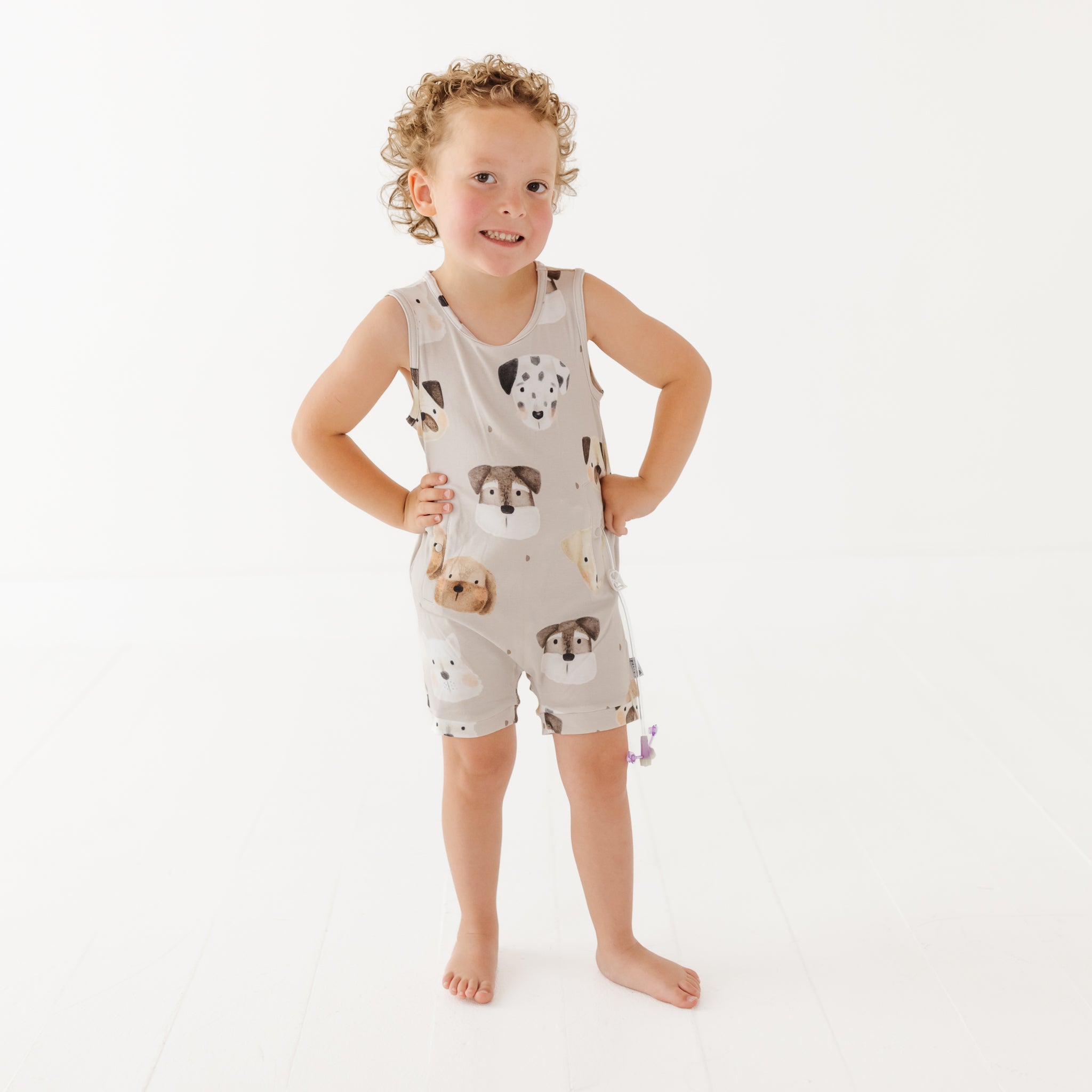 Child wearing a sleeveless romper with dog prints on a white background