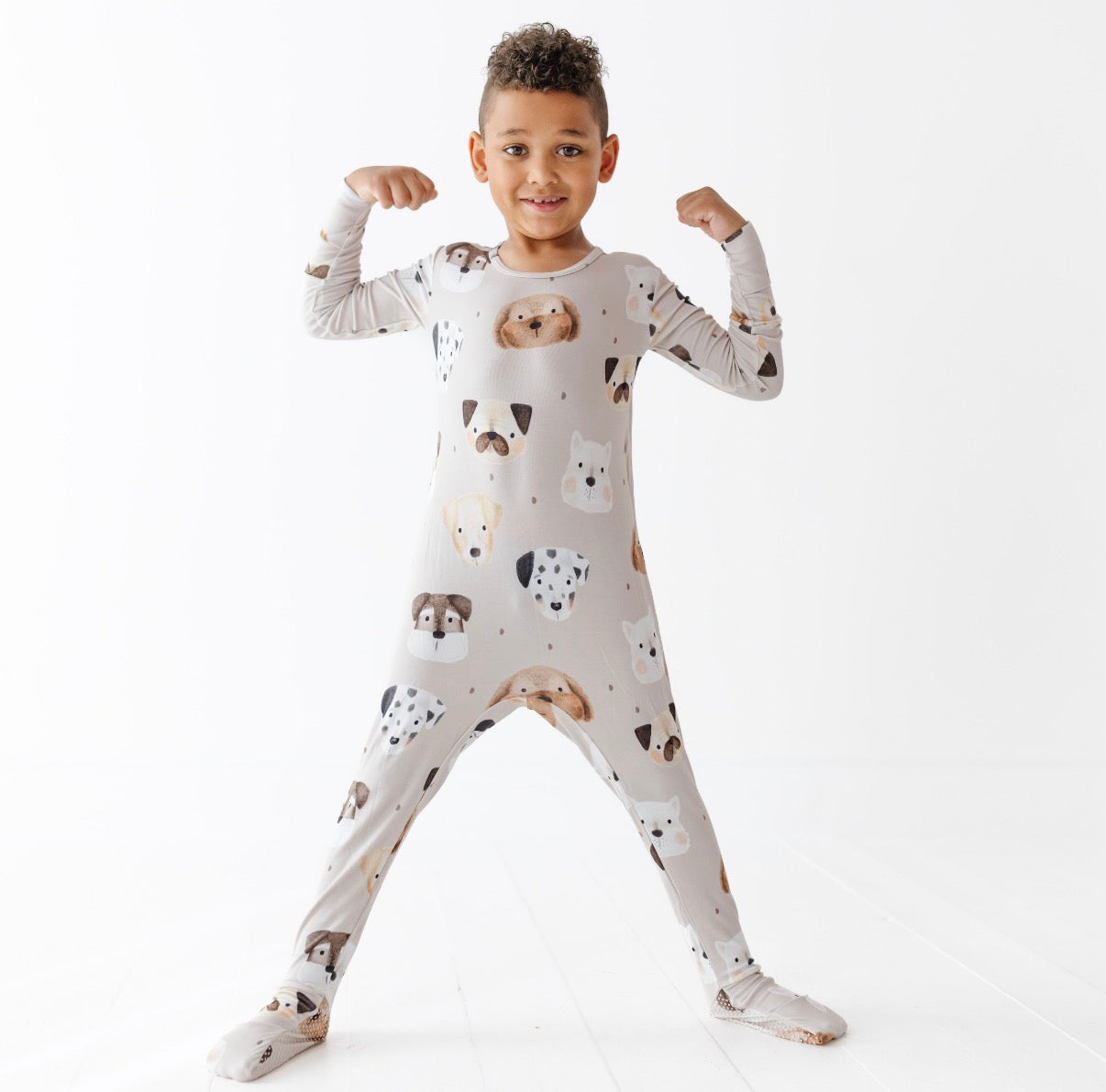 Child wearing a white onesie with dog pattern on a white background