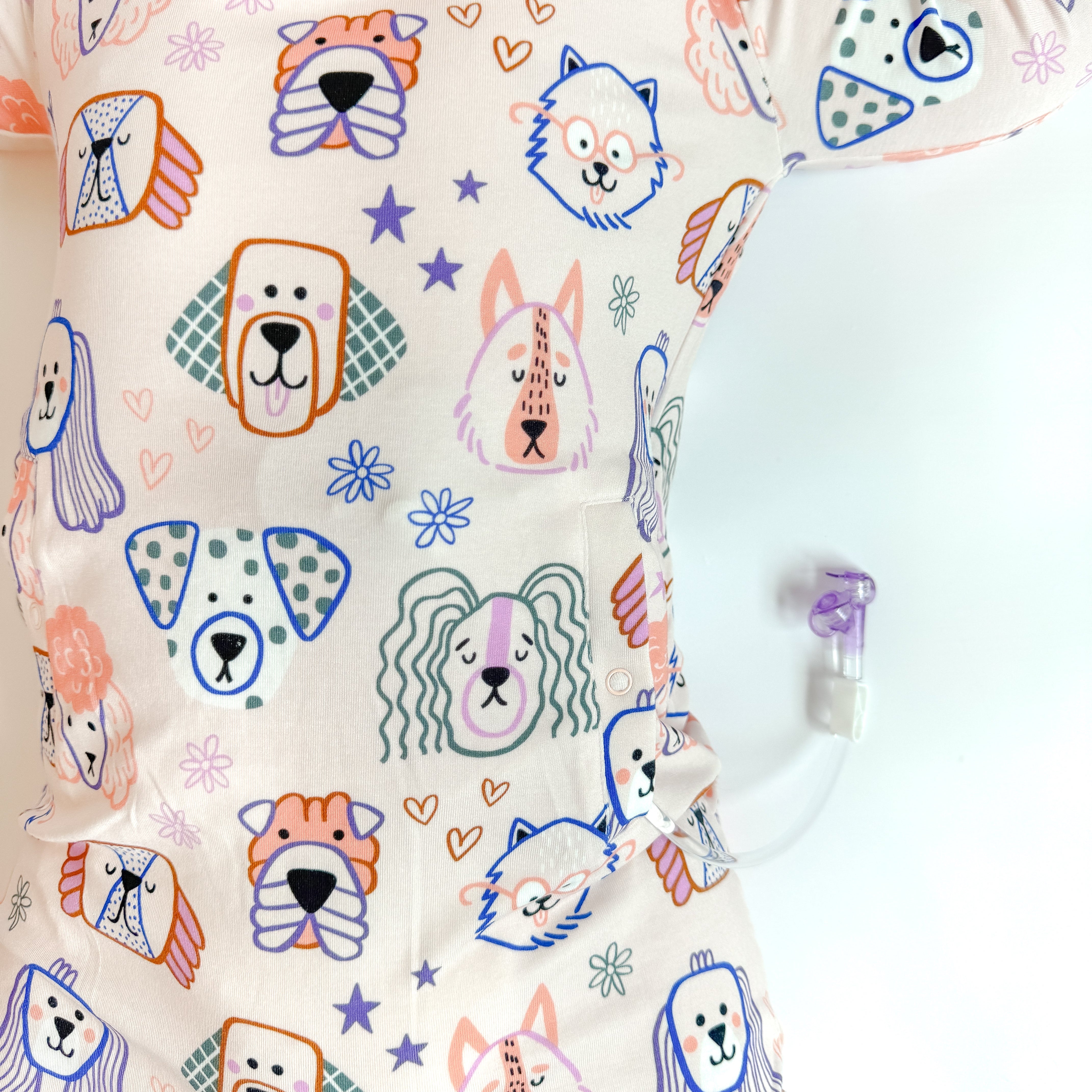 Baby wearing a onesie with colorful dog illustrations on a white background