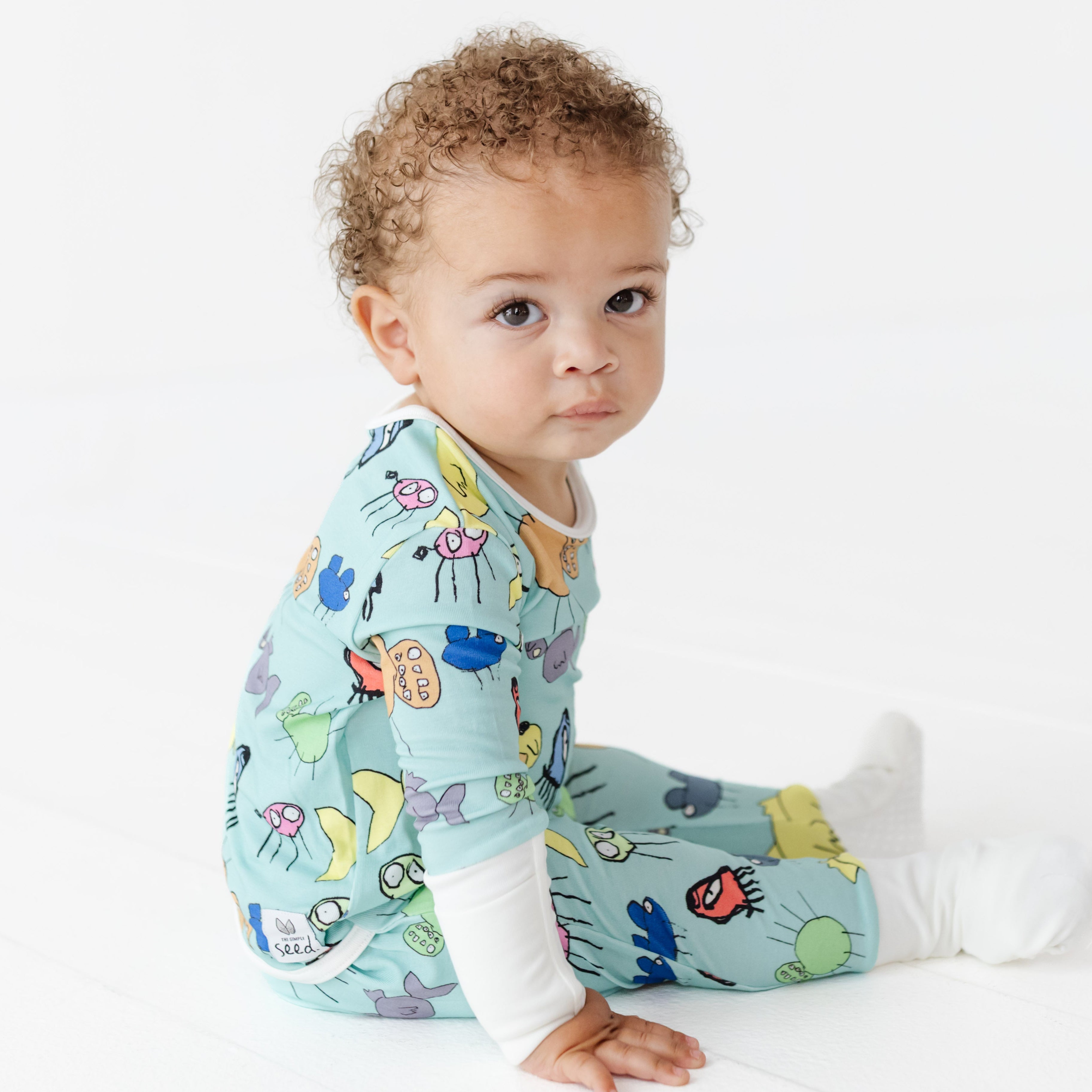Baby wearing a colorful outfit with animal patterns on a white background