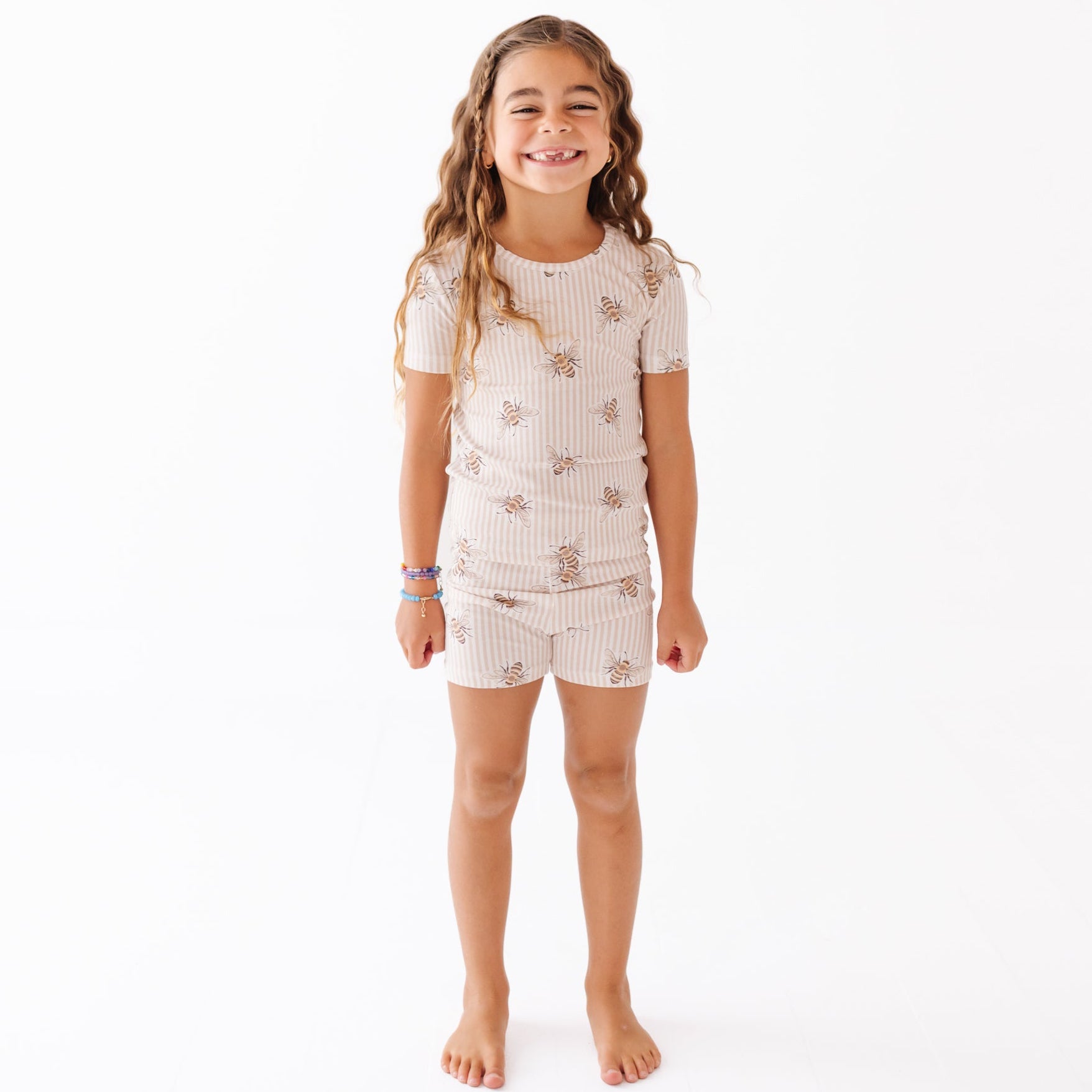 Girl wearing outfit with stripes and bees on a white background 