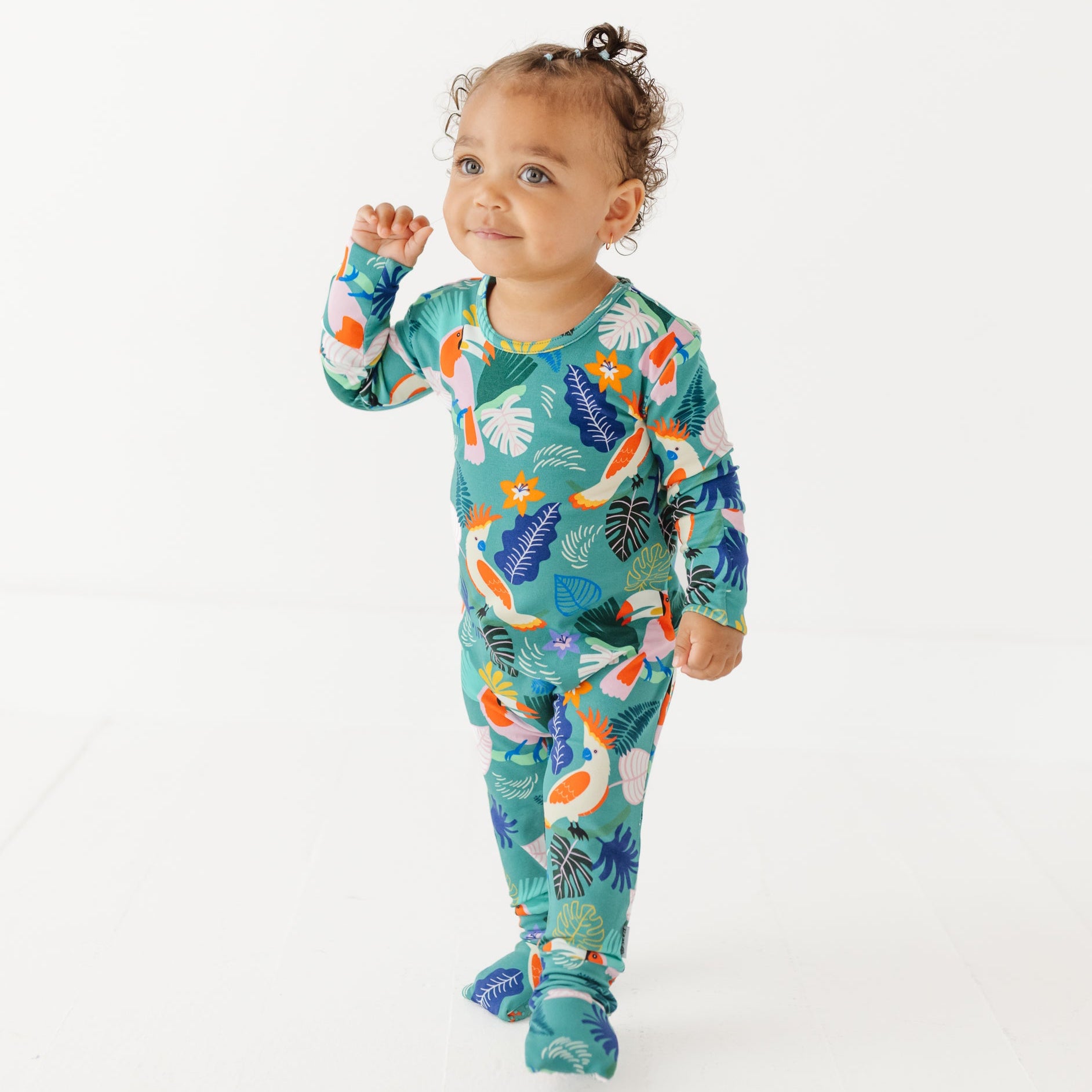 Baby wearing a colorful onesie with a floral pattern on a white background