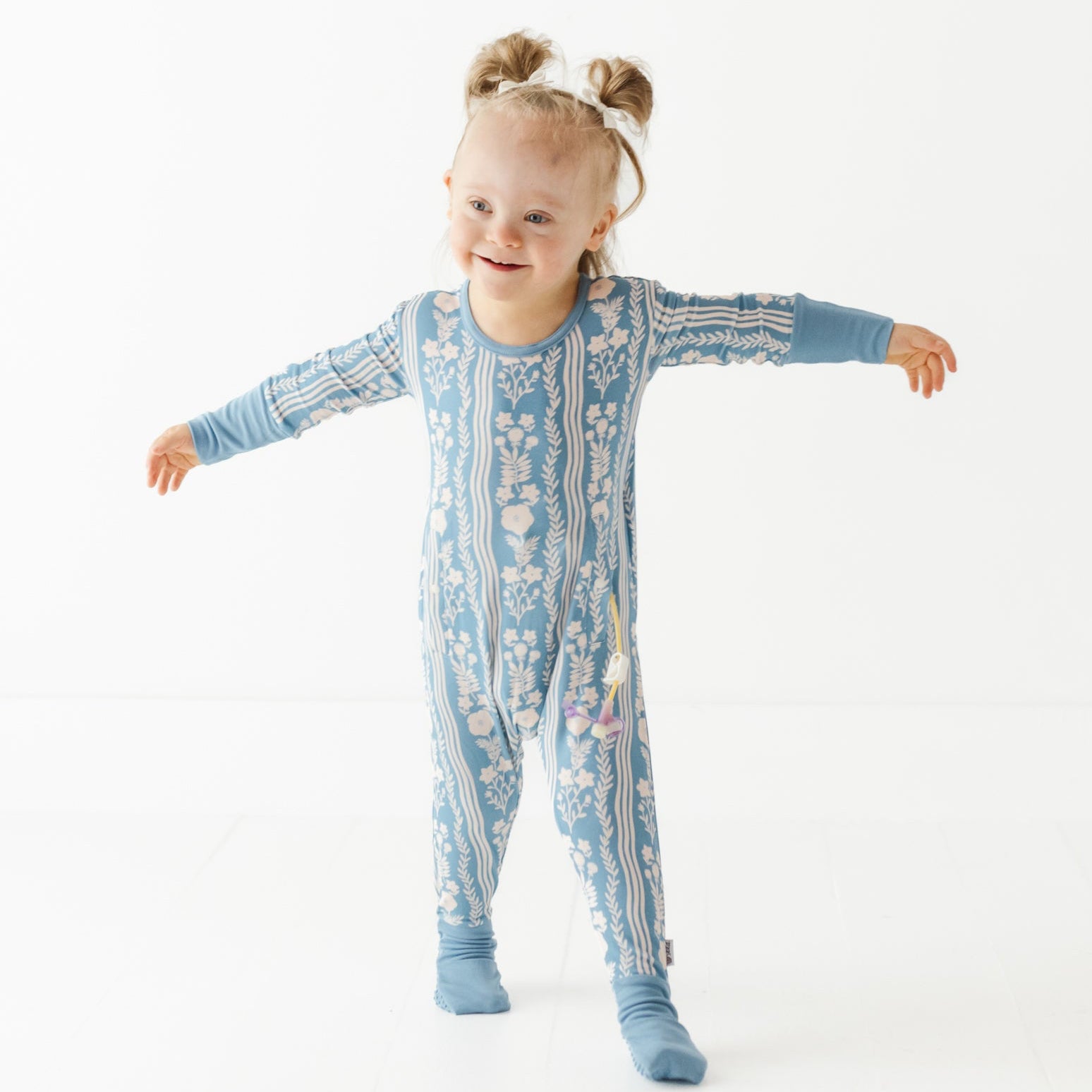 Child wearing a blue patterned onesie on a white background