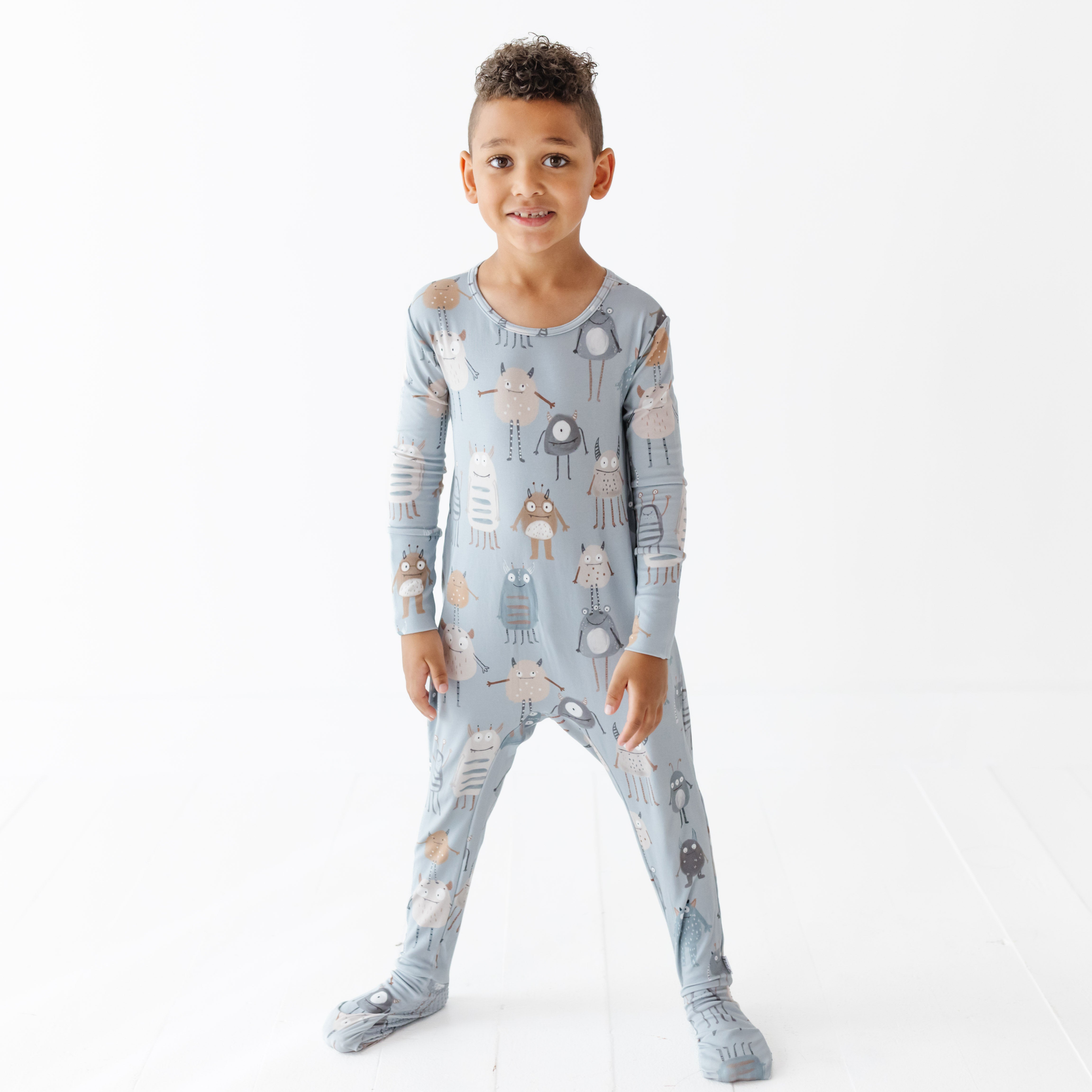 Child wearing a blue onesie with animal patterns on a white background