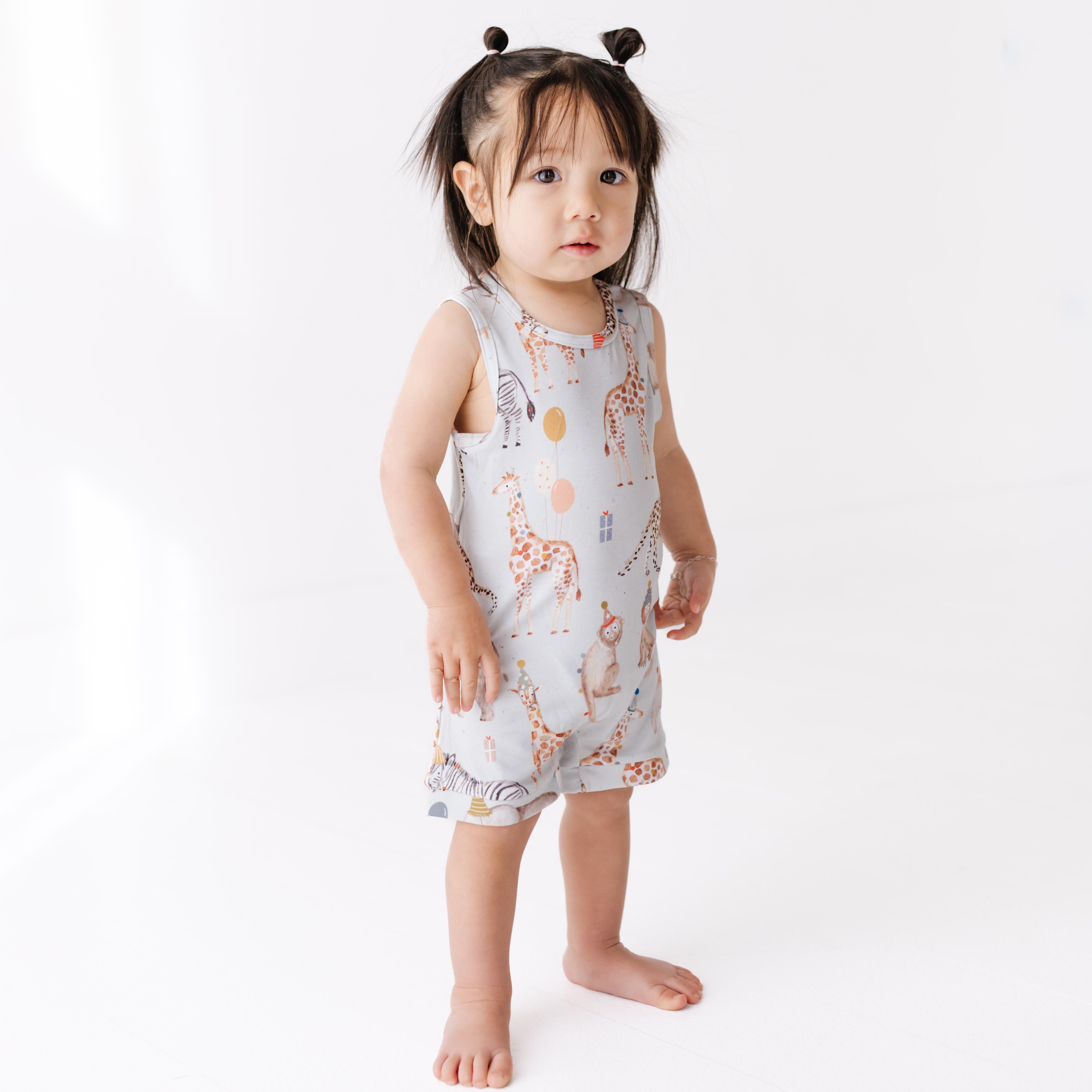 Child wearing a sleeveless dress with animal print on a white background