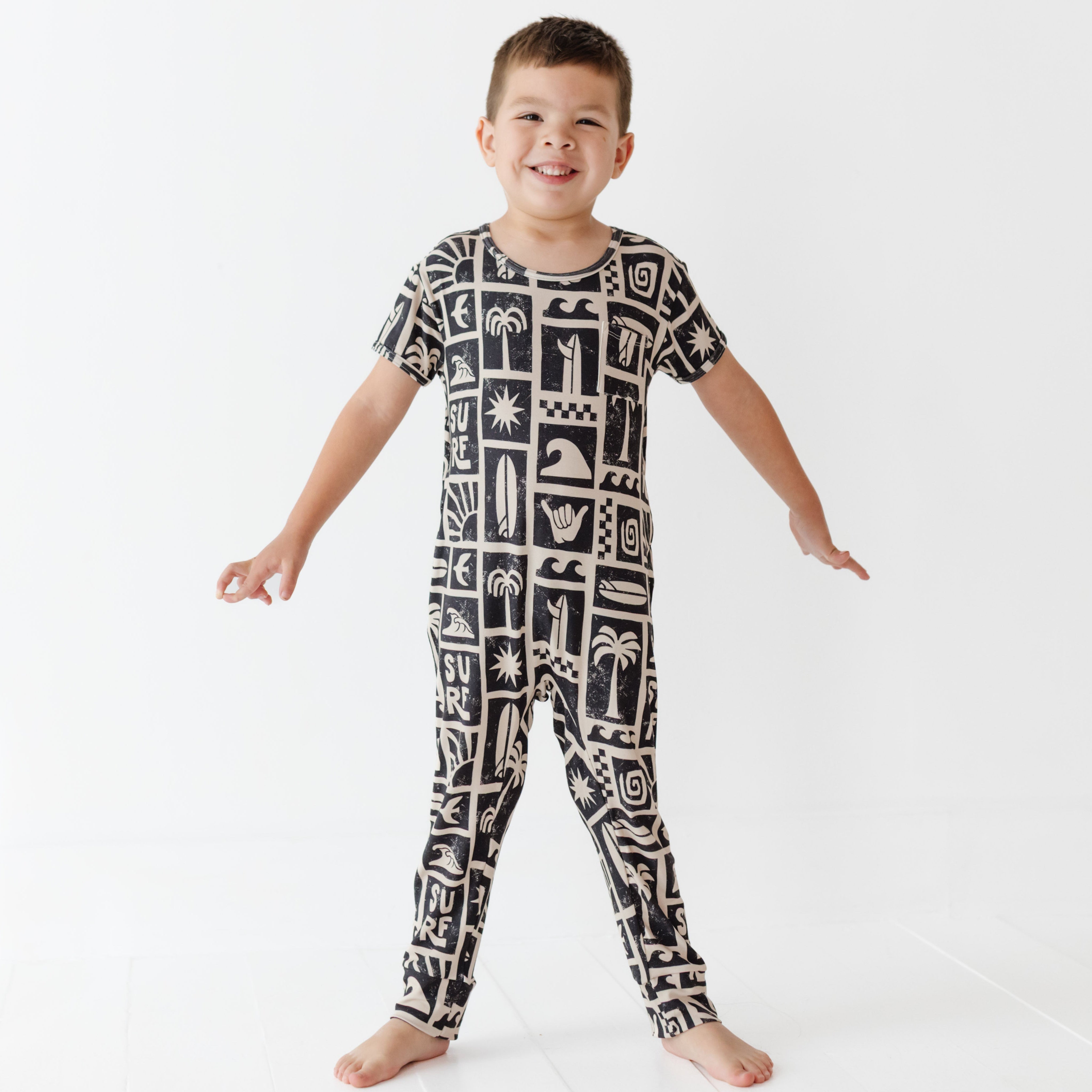 Child wearing a black and white patterned onesie on a white background