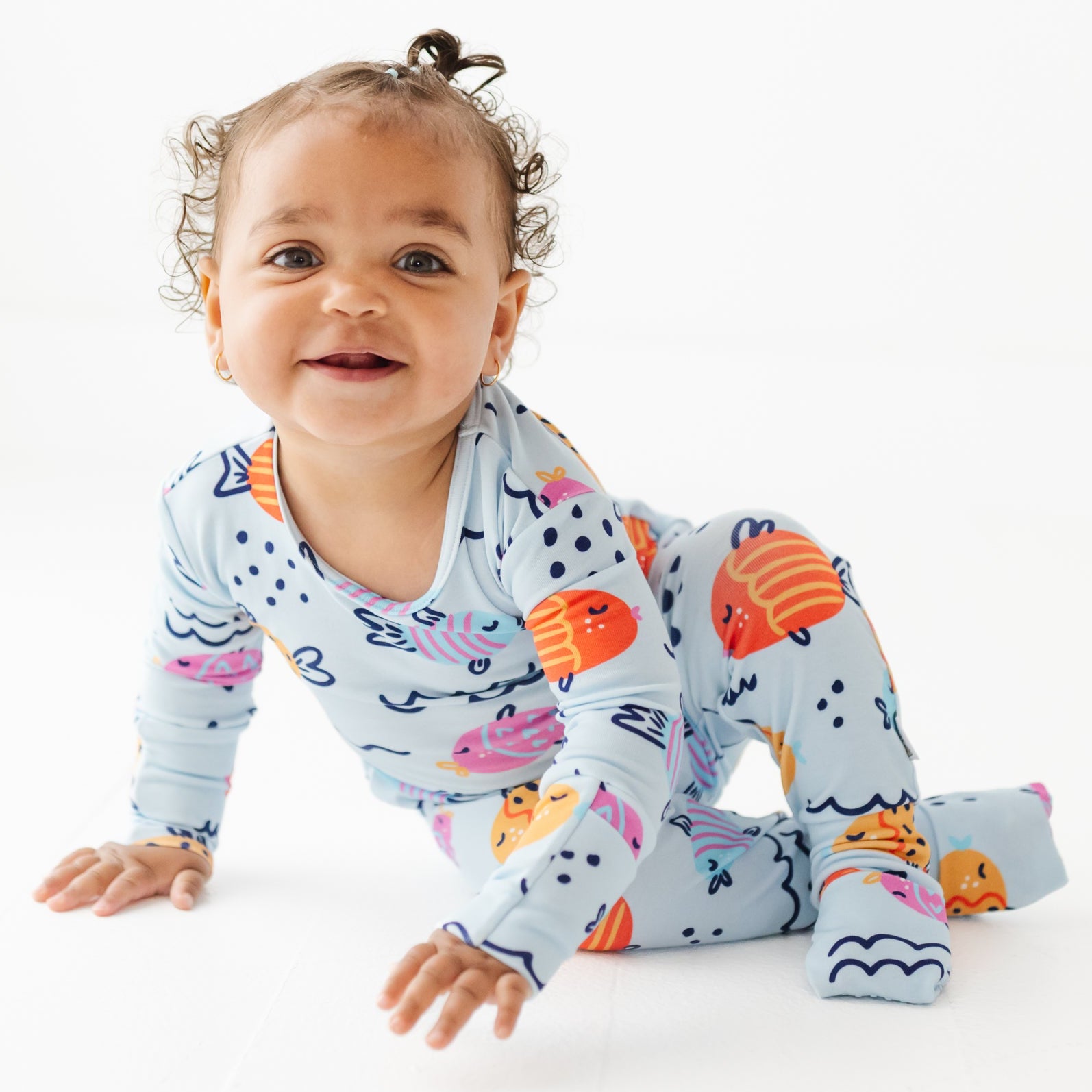 Baby wearing a colorful onesie with sea-themed design on a white background