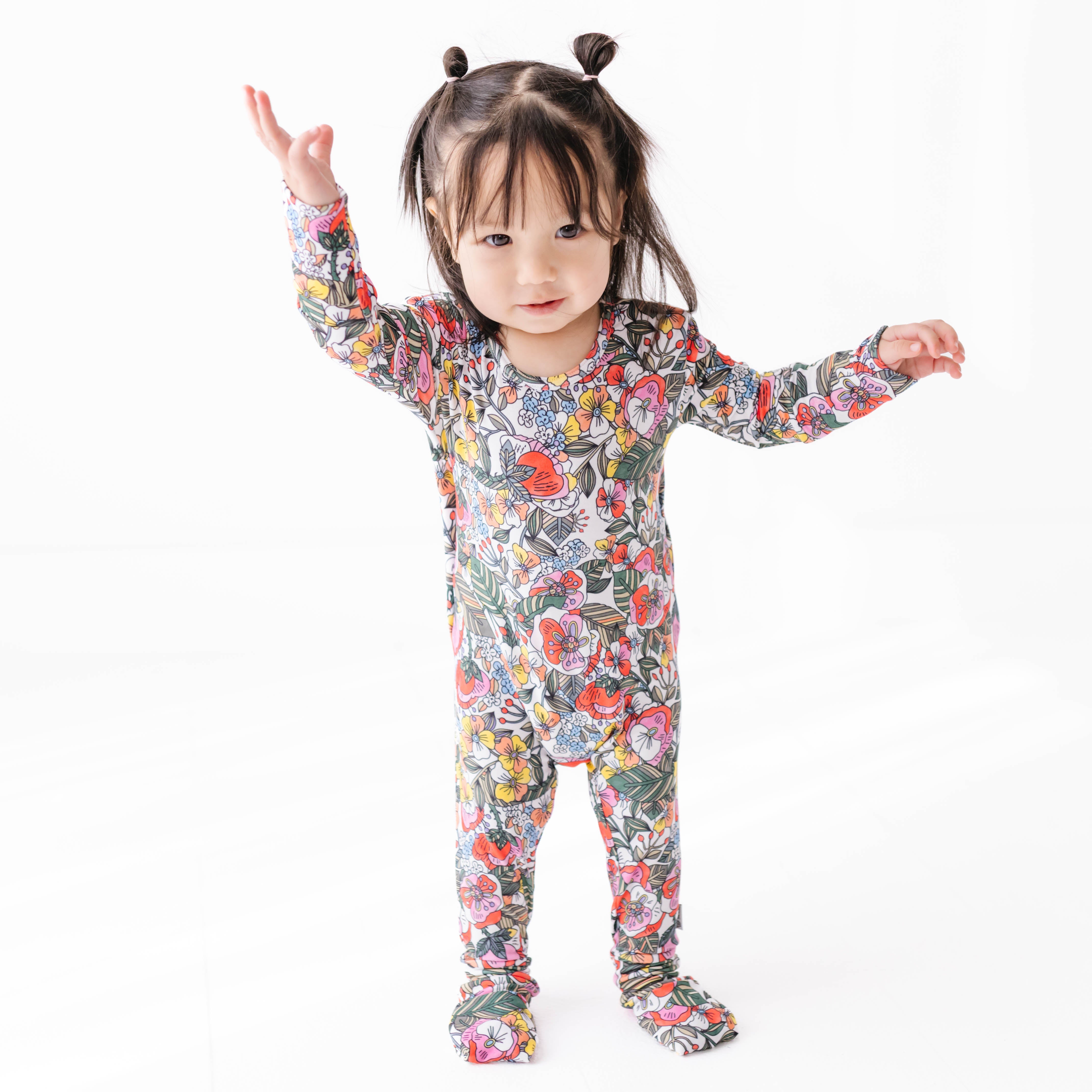 Child wearing a colorful floral onesie on a white background