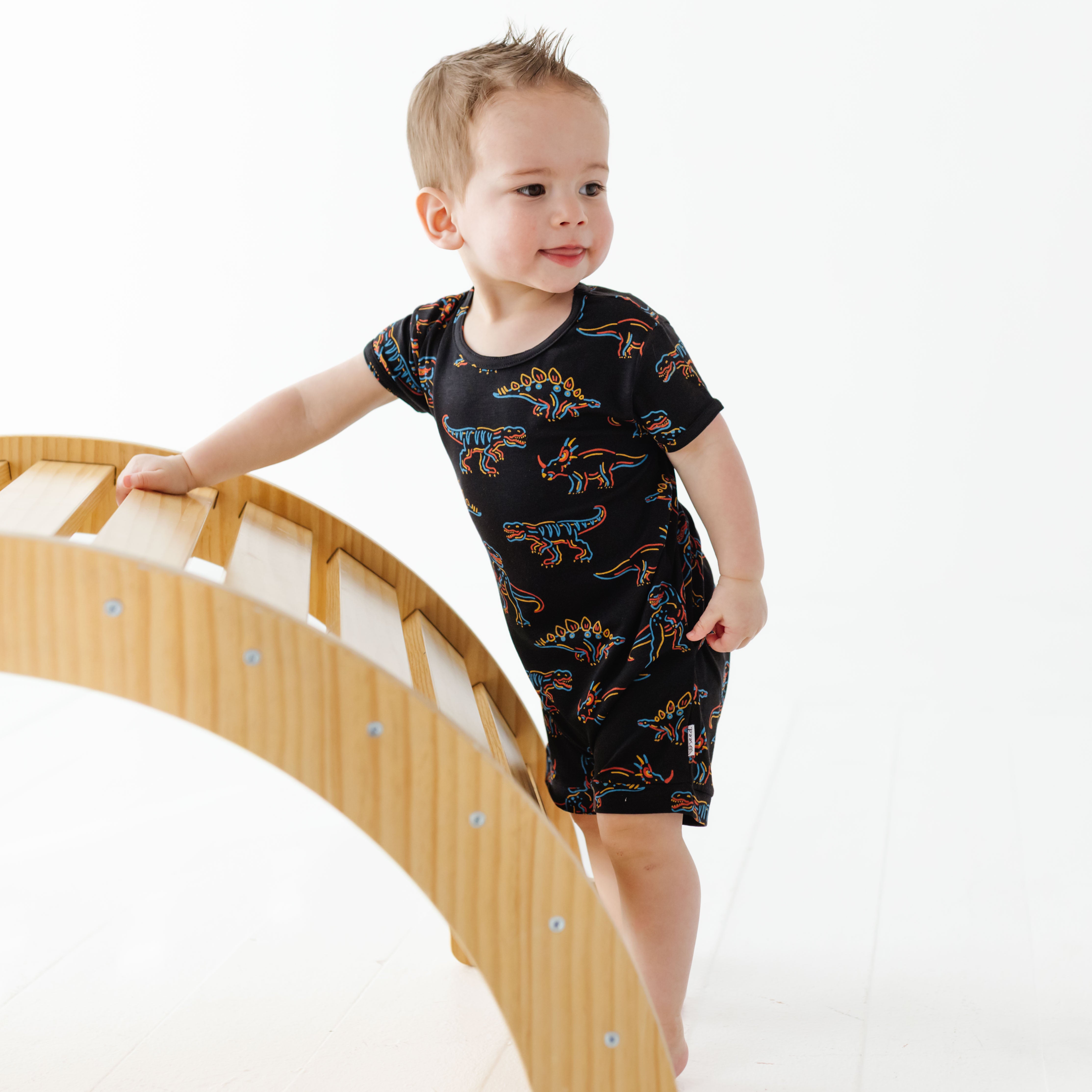 Child wearing a black t-shirt with dinosaur prints on a white background