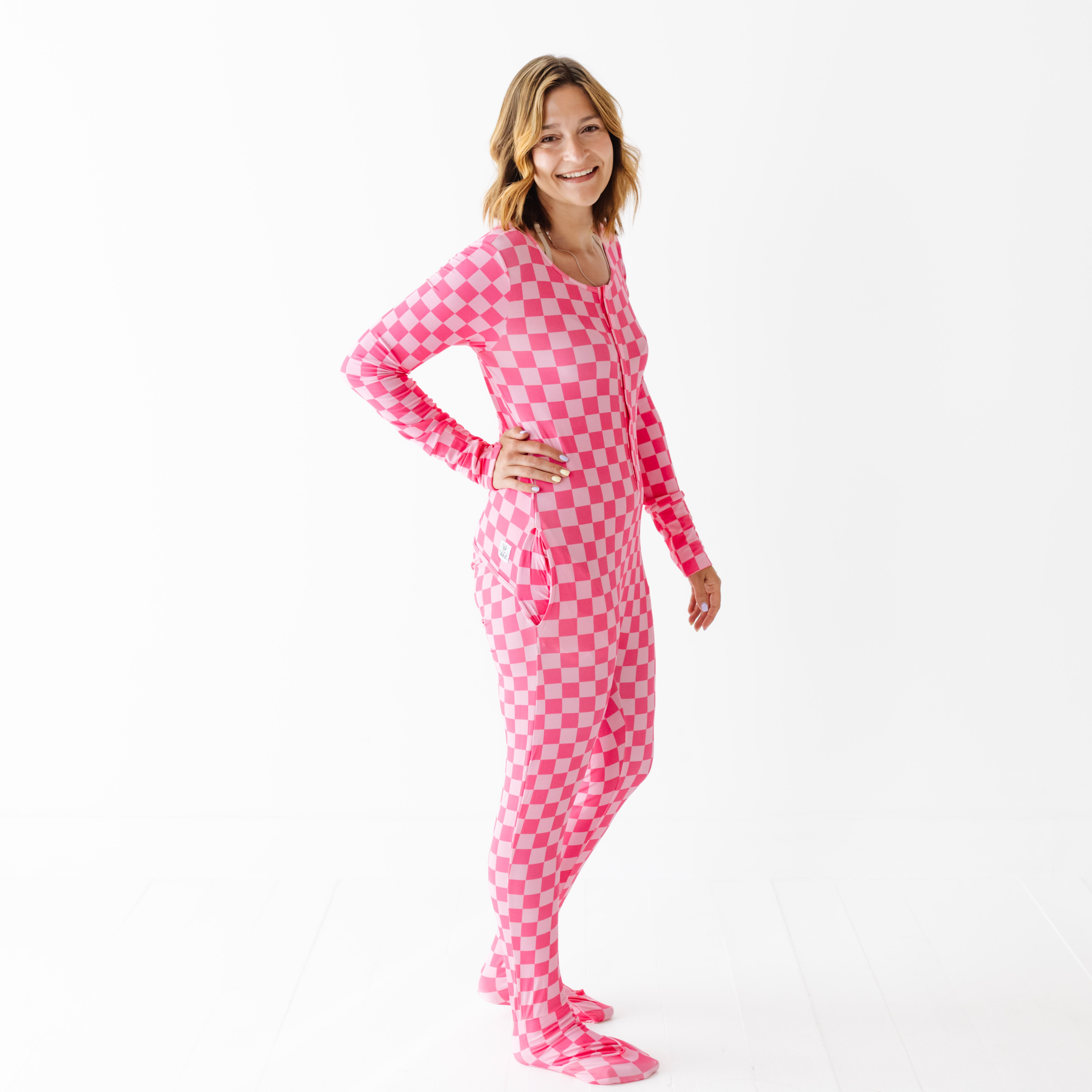 Woman wearing pink checkered footie pajamas on a white background
