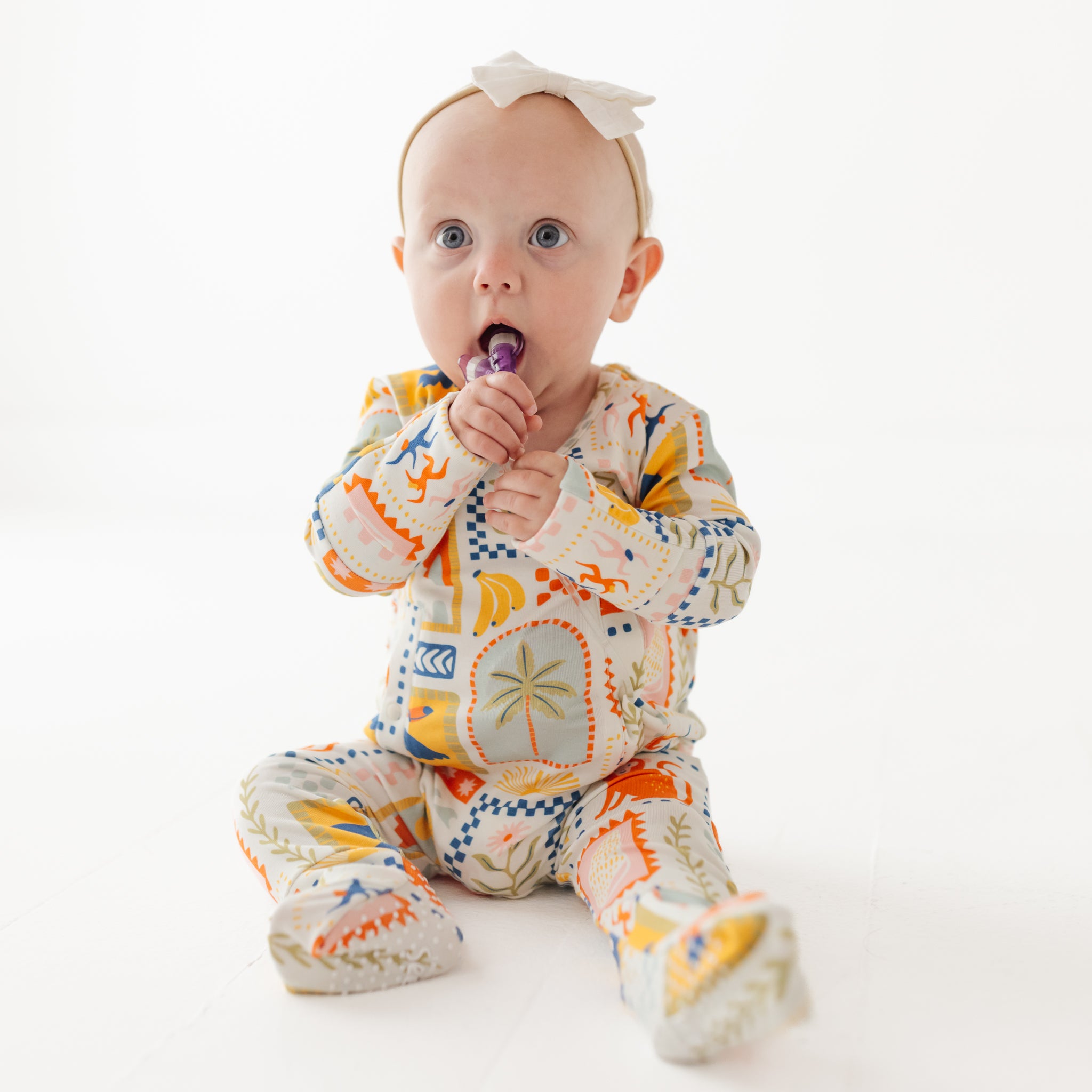 Baby wearing a colorful onesie on a white background