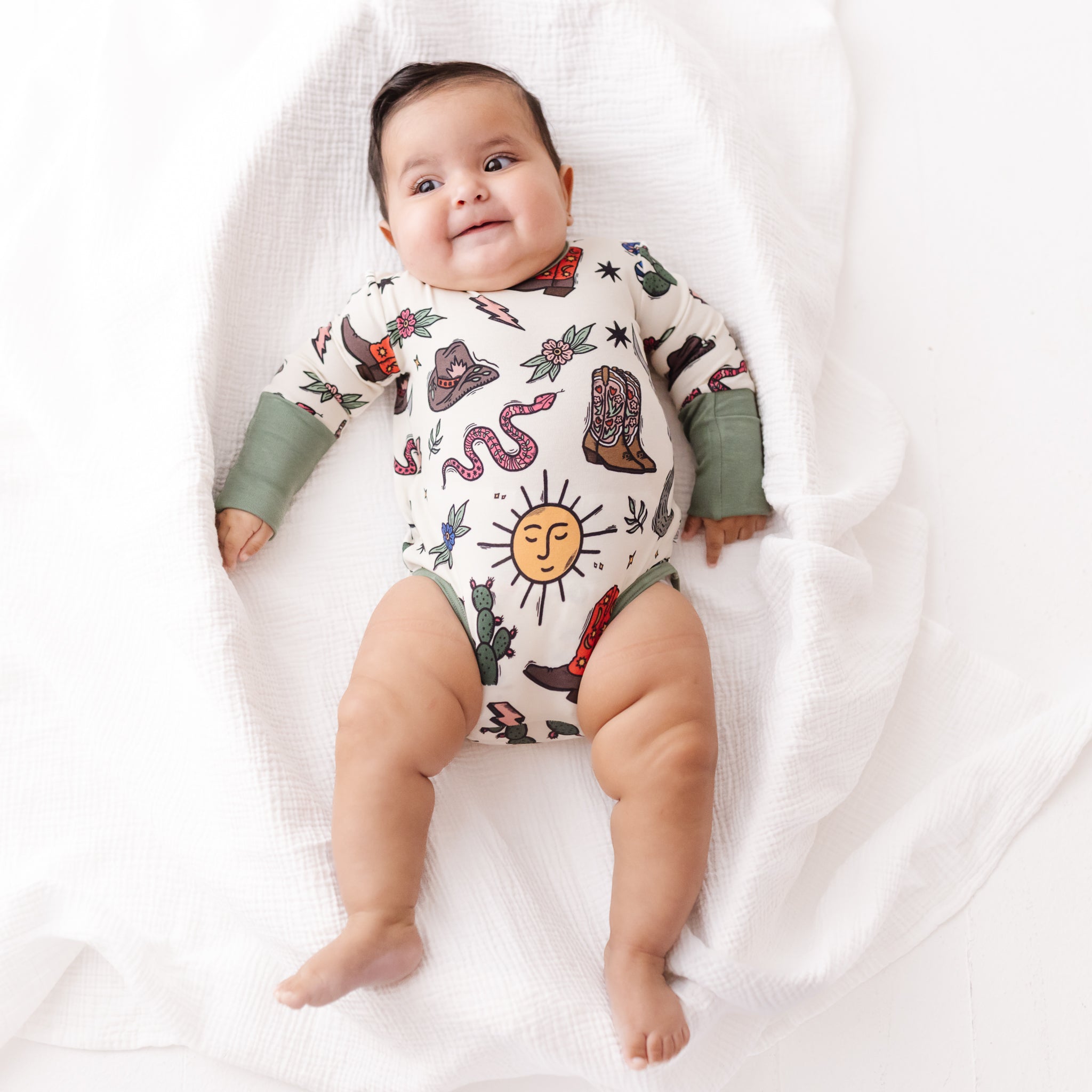 Baby wearing a patterned onesie on a white blanket