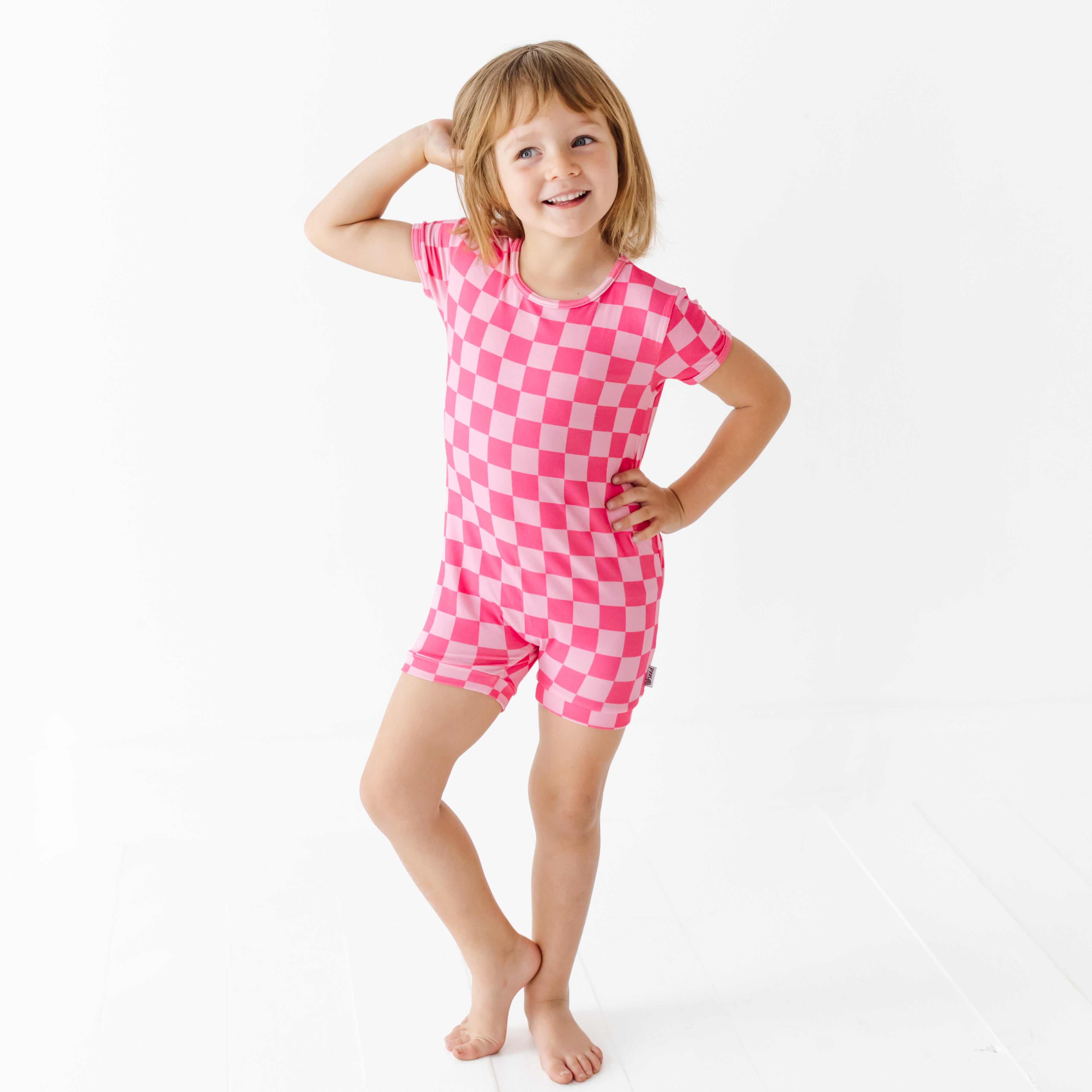 Child wearing a pink checkered outfit on a white background