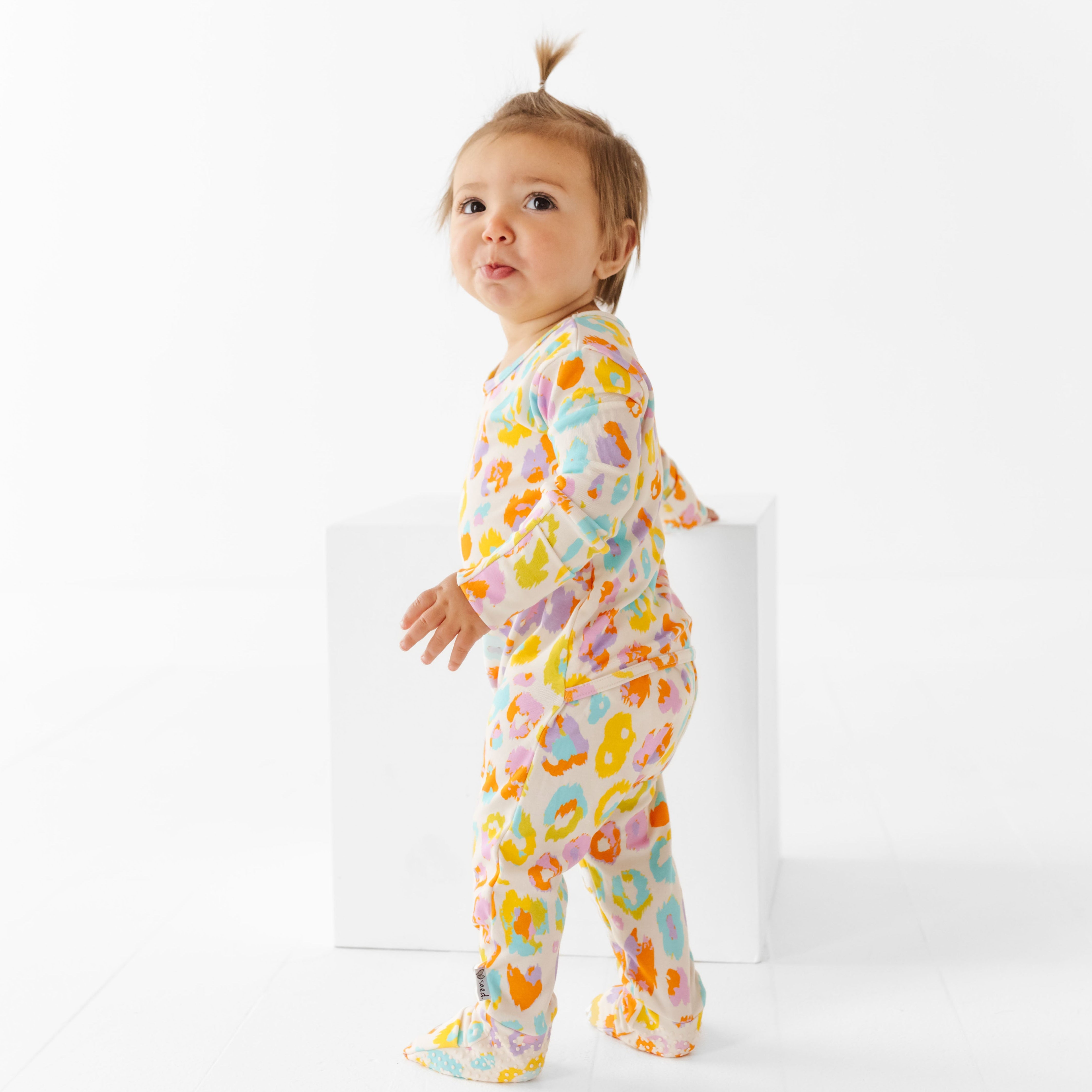 Baby wearing a colorful leopard print onesie on a white background
