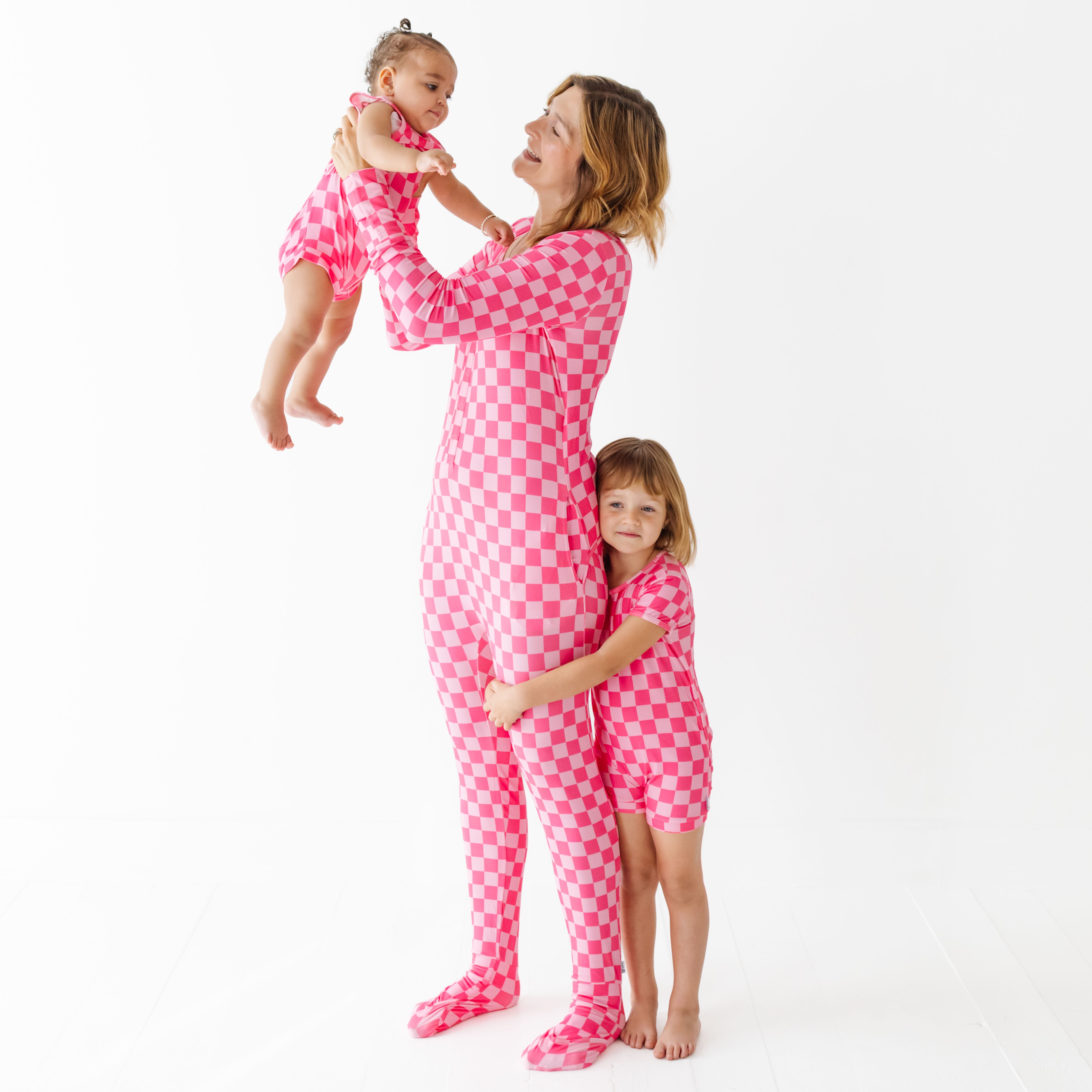 Woman and two children wearing matching pink checkered pajamas on a white background