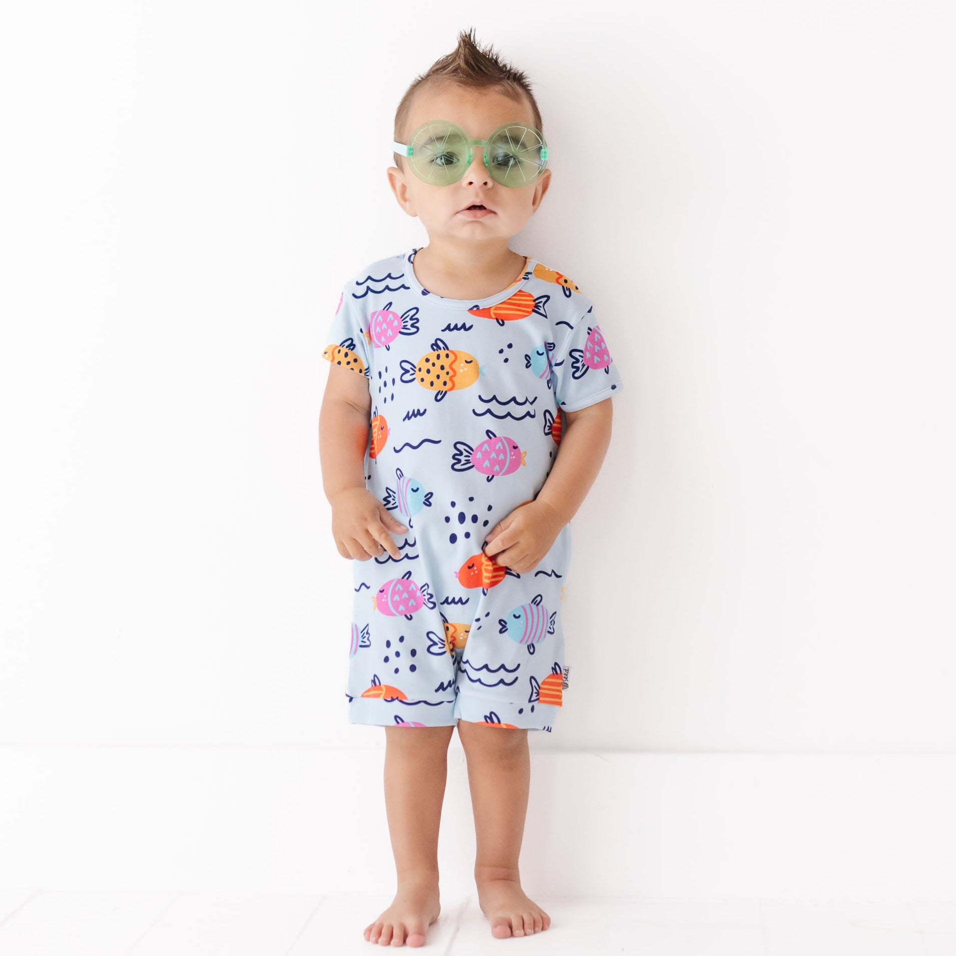 Child wearing a colorful fish-themed outfit with goggles on a white background