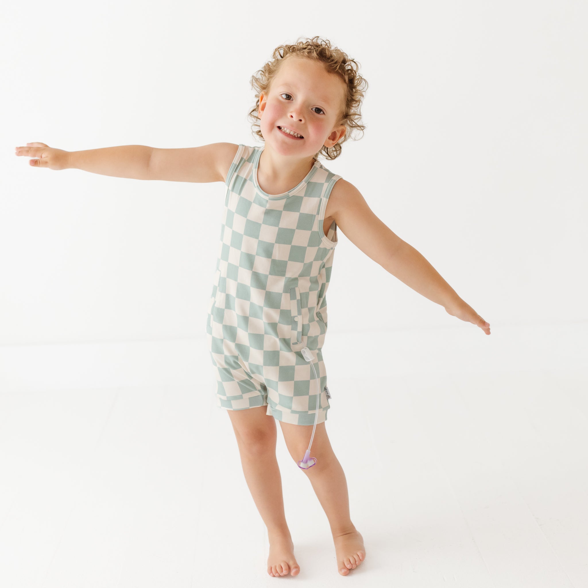 Child wearing a checkered romper on a white background