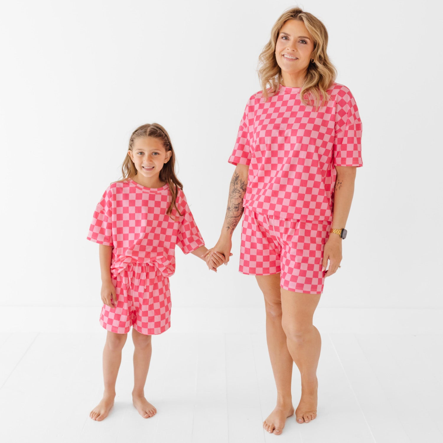 Woman and child wearing matching pink checkered outfits on a white background