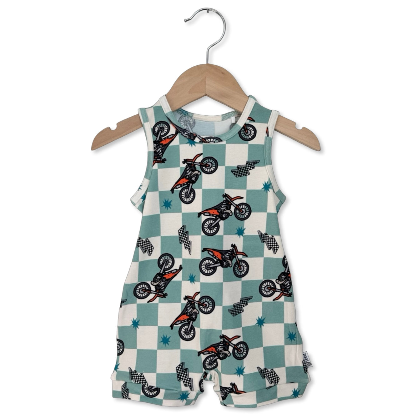Children's romper with dirt bike pattern on a hanger against a white background