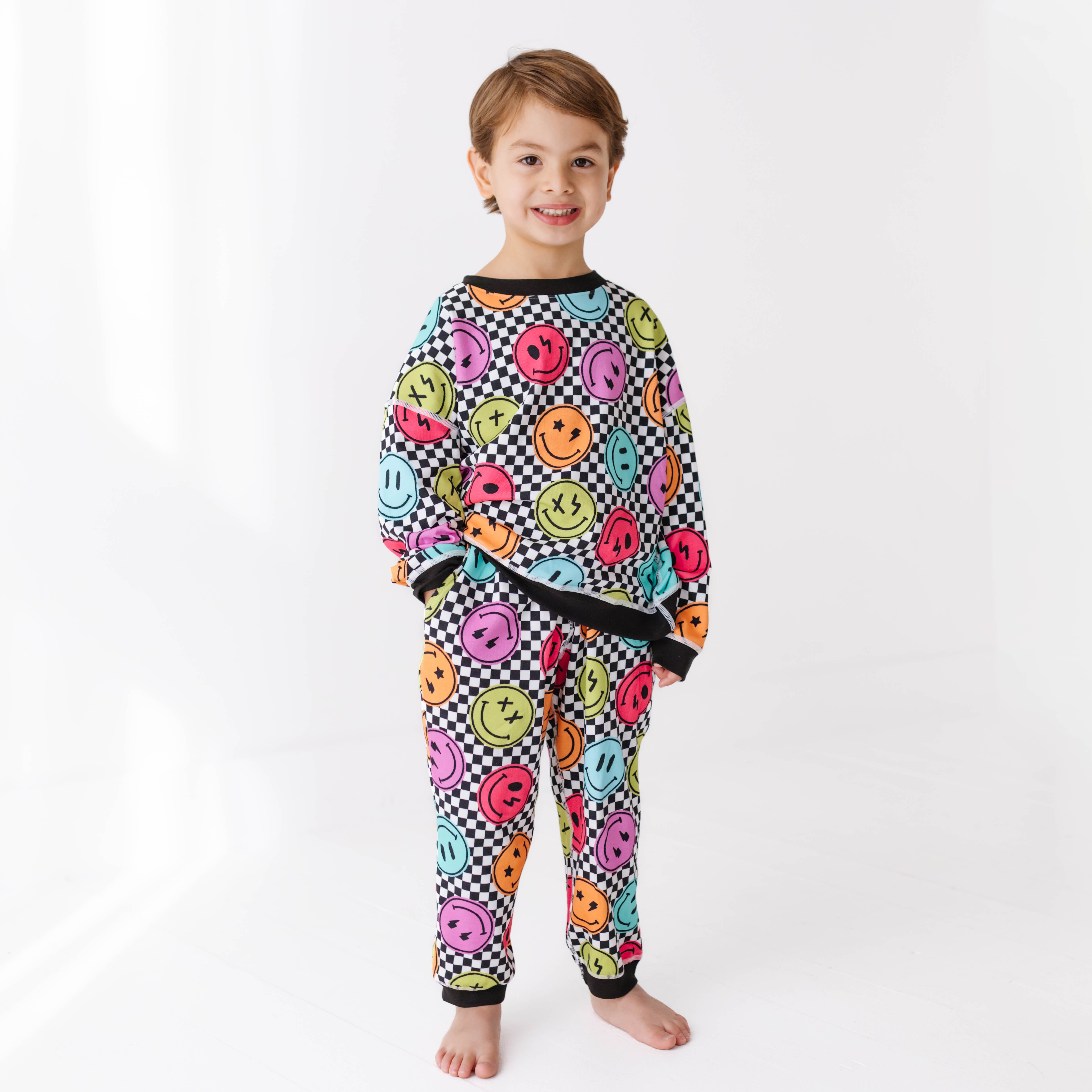 Child wearing a colorful sweat set with smiley face pattern on a white background