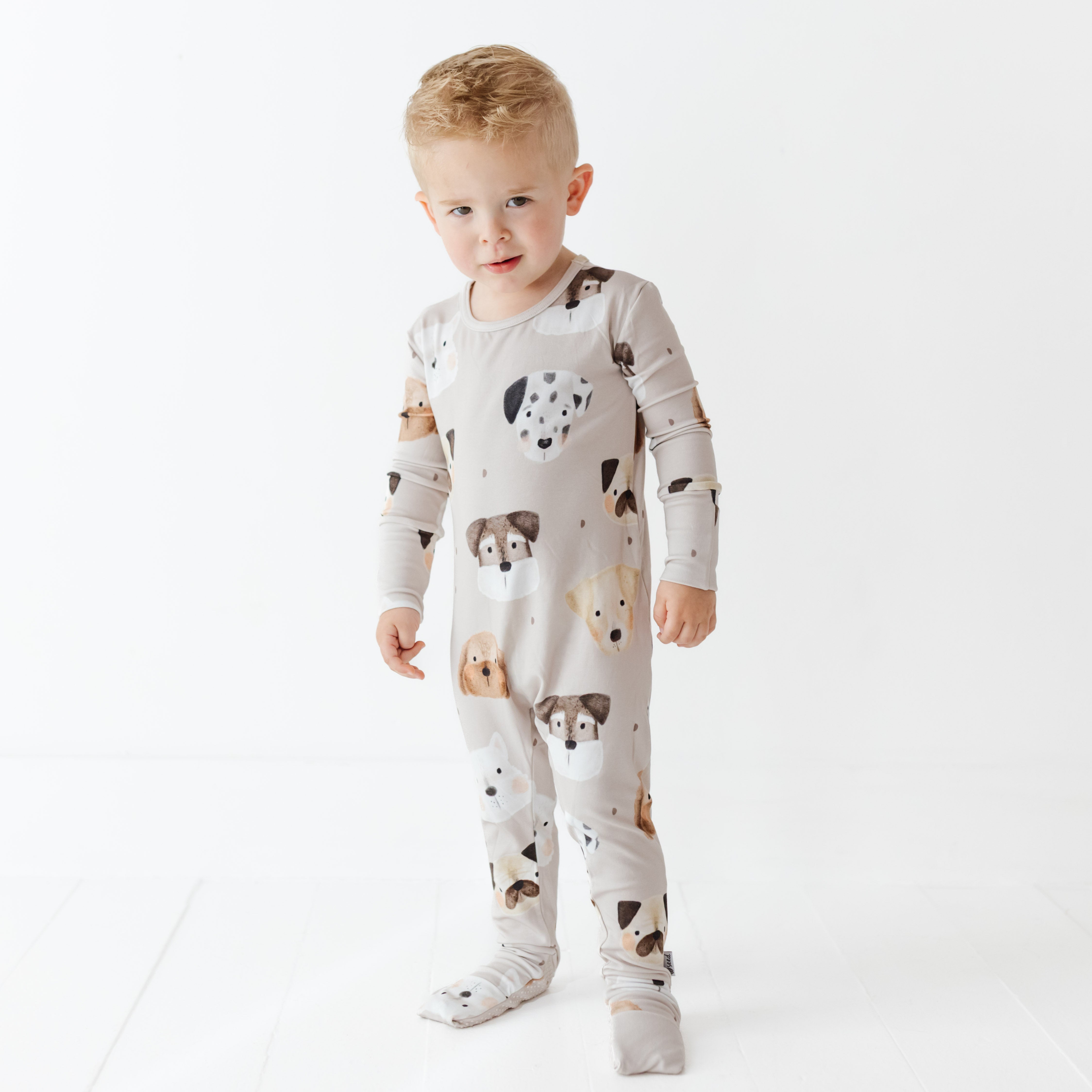 Child wearing a onesie with dog pattern on a white background