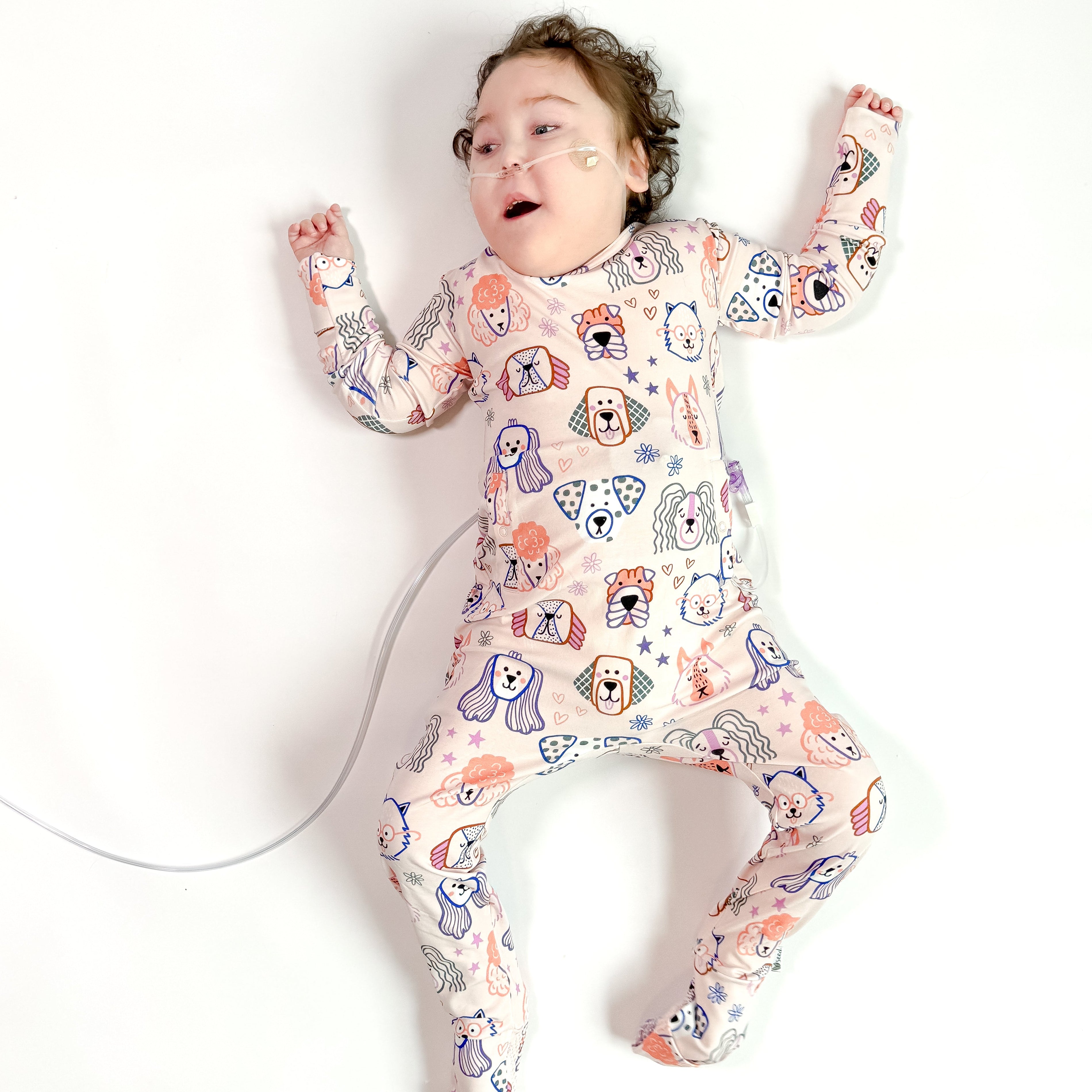 Child wearing a colorful onesie with animal patterns on a white background