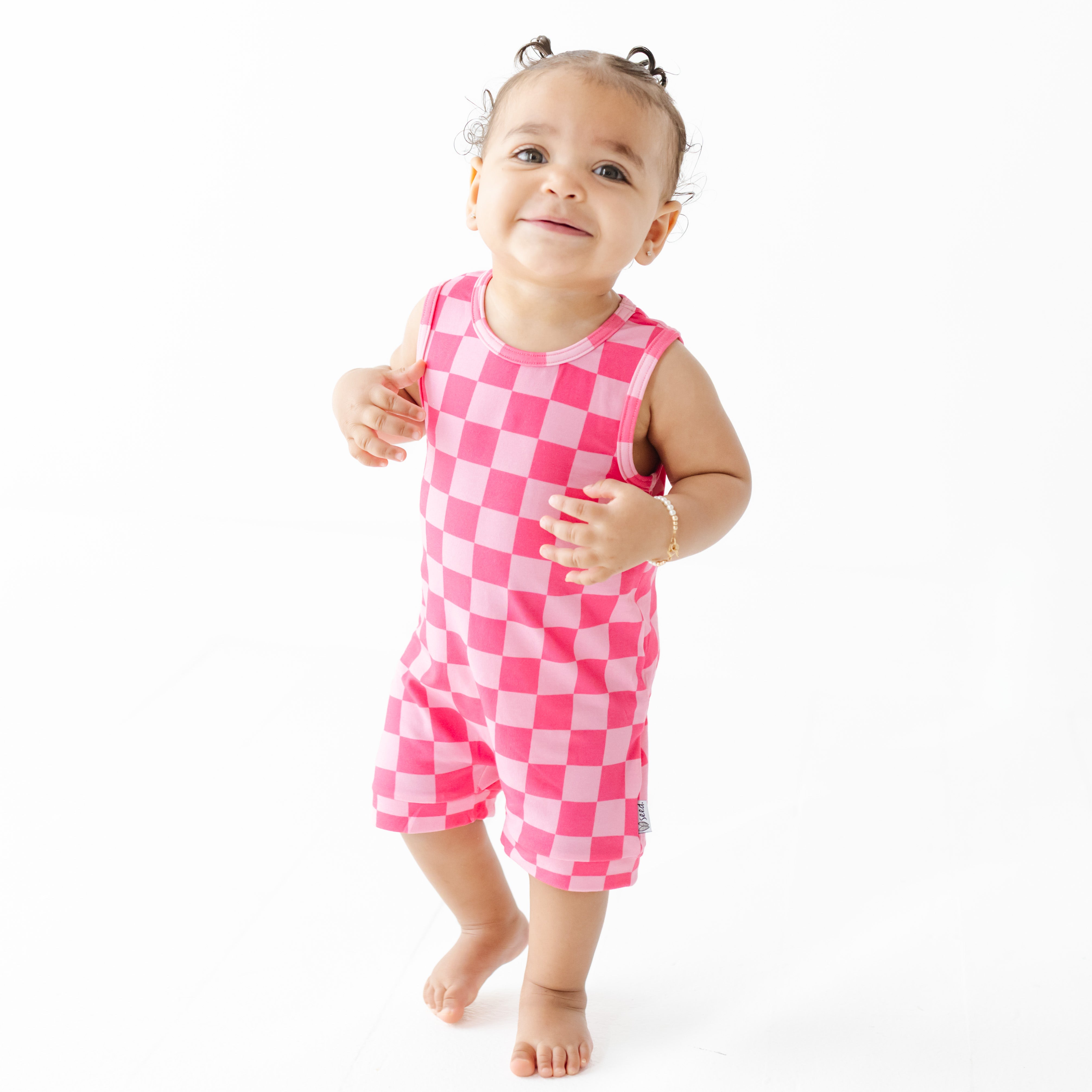 Baby wearing a pink checkered outfit on a white background