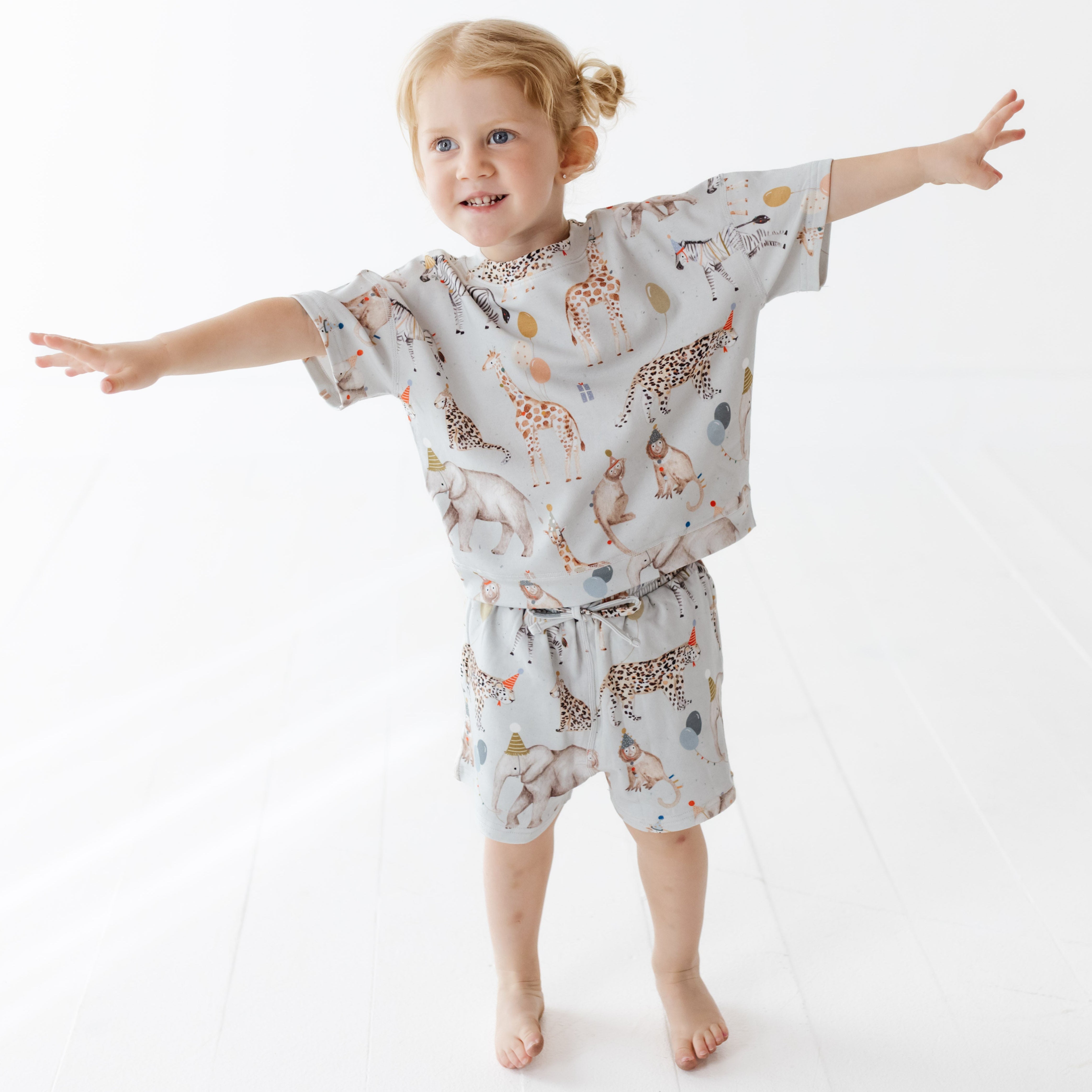 Child wearing a patterned outfit with animal designs on a white background