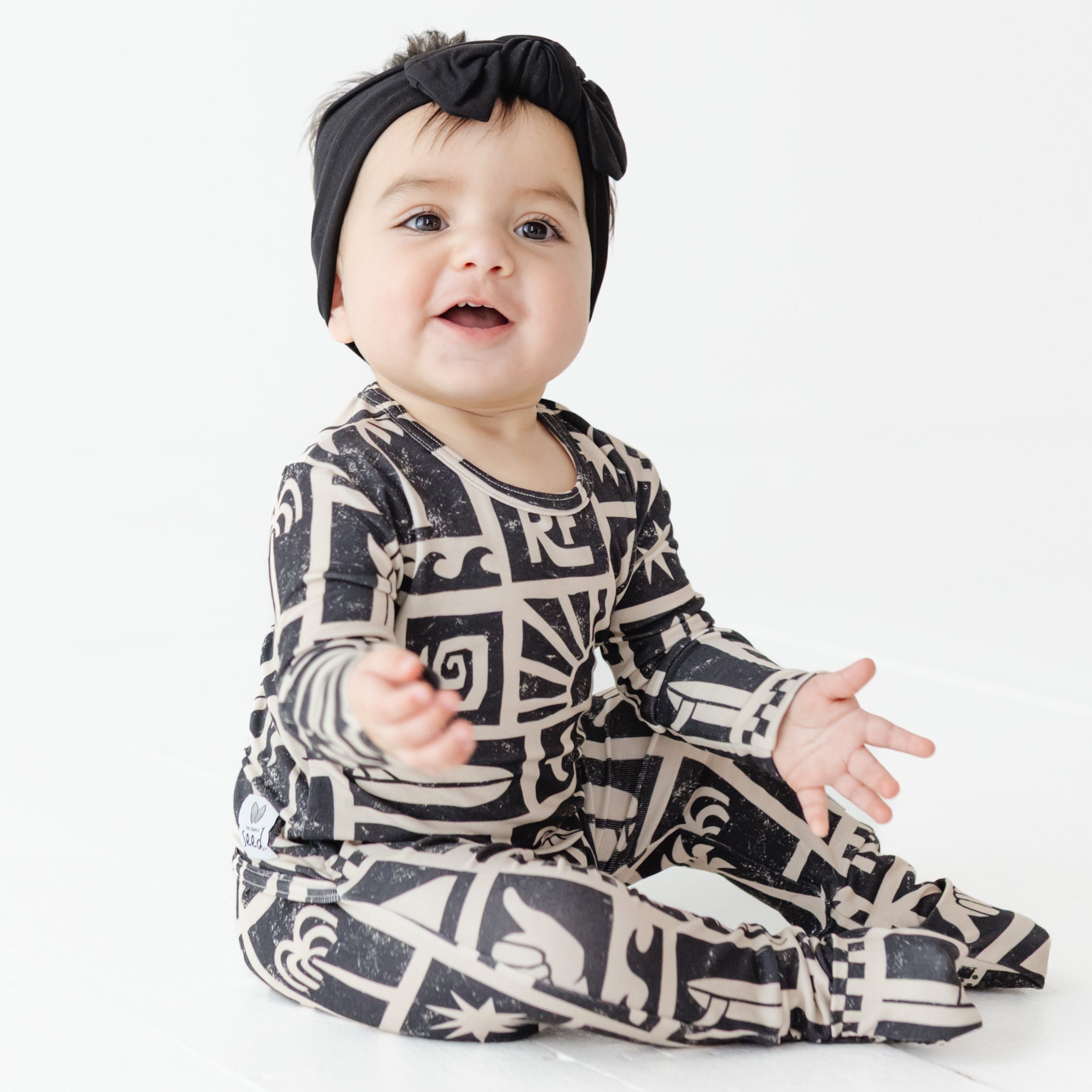 Baby wearing a black and white patterned outfit on a white background
