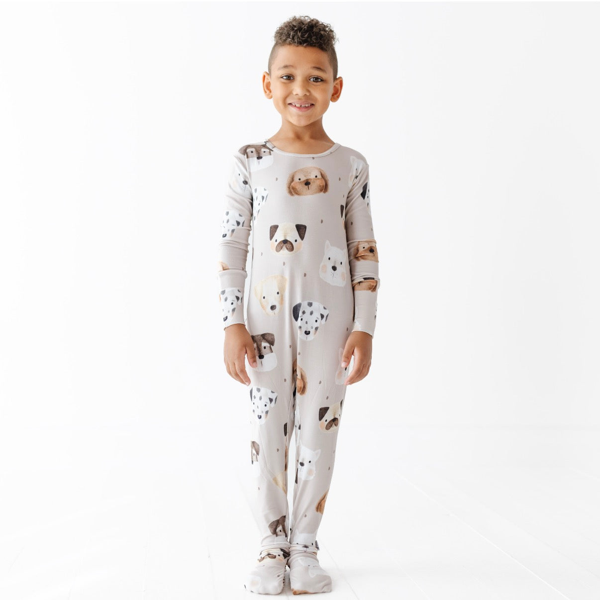 Child wearing a white onesie with animal prints on a white background