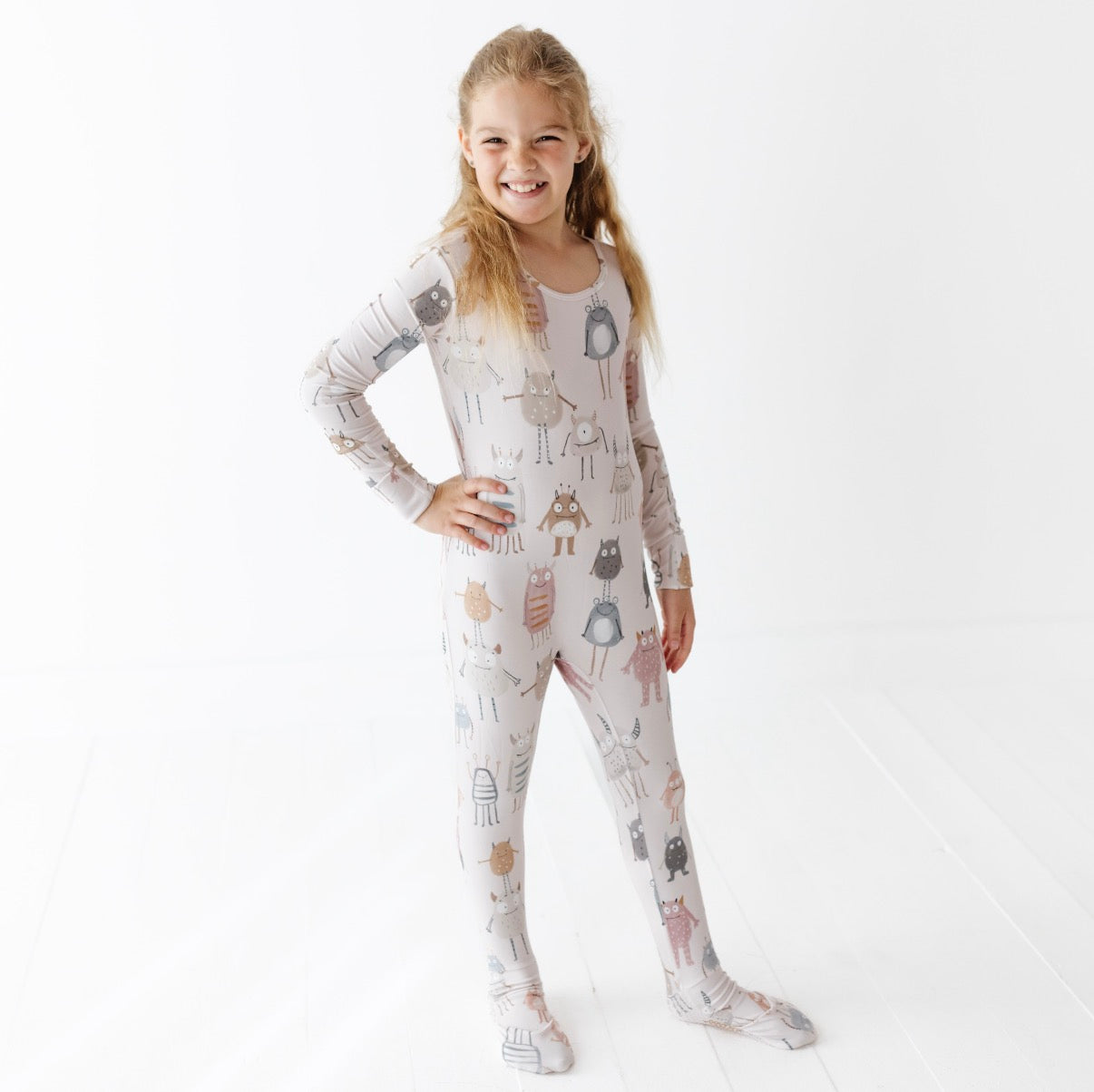Young girl wearing a patterned onesie on a white background