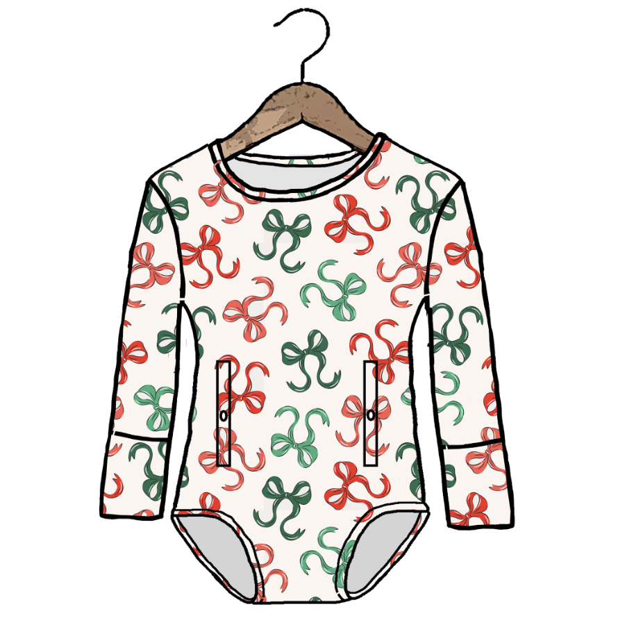 A long-sleeve baby bodysuit with an all-over repeating pattern of red and green abstract squiggle motifs on a warm off-white background, hanging on a wooden hanger against a solid white background.