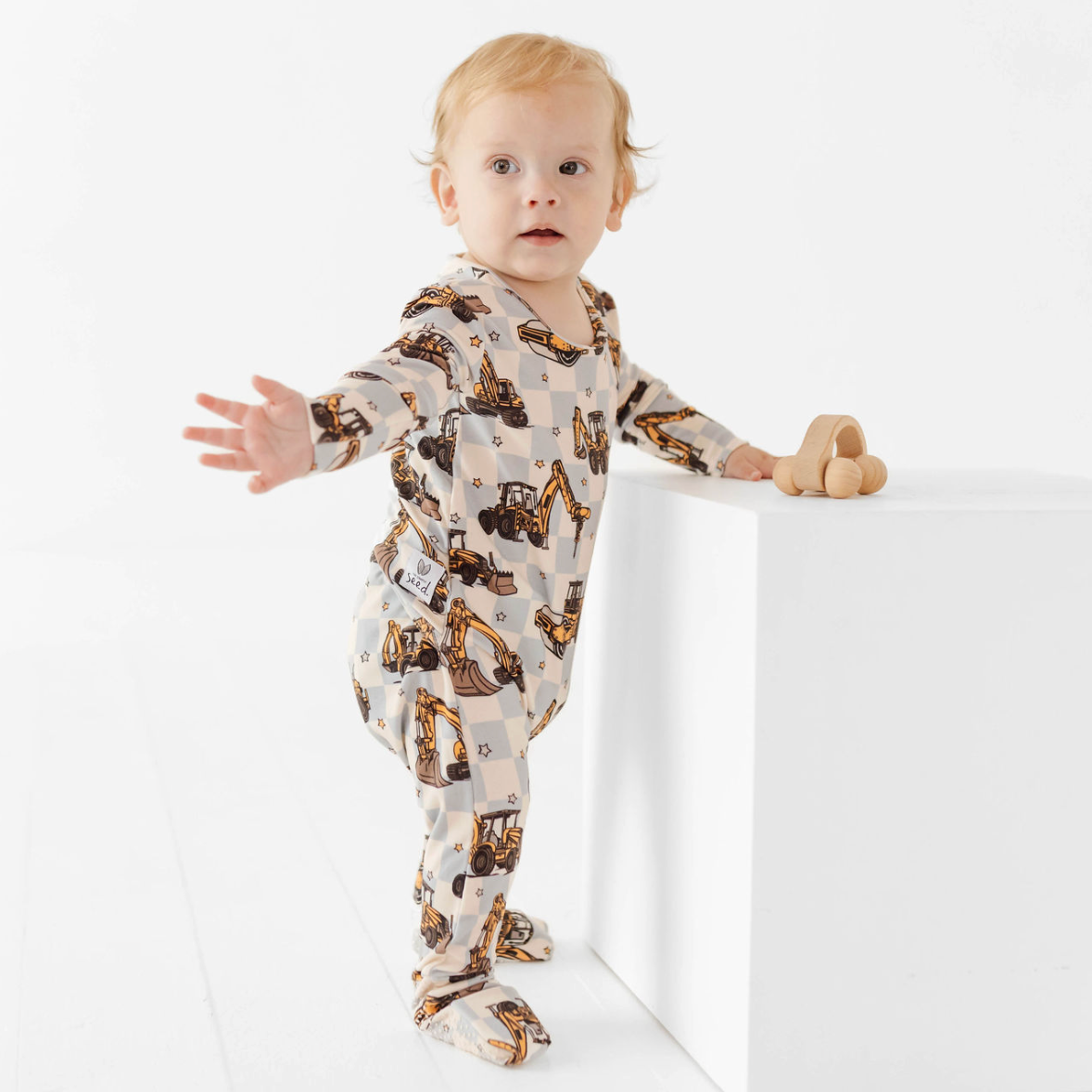 Baby wearing a onesie with animal print standing on a white surface