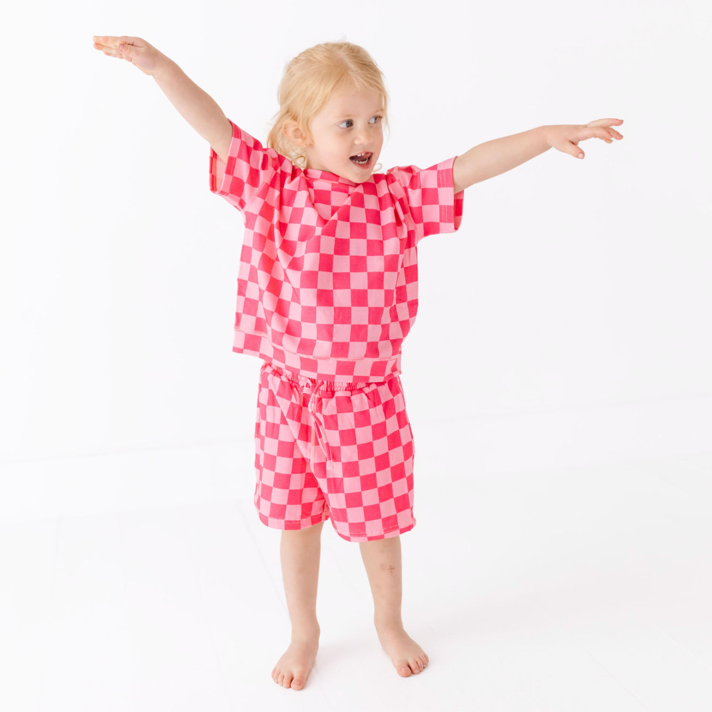 Child wearing a pink checkered outfit on a white background