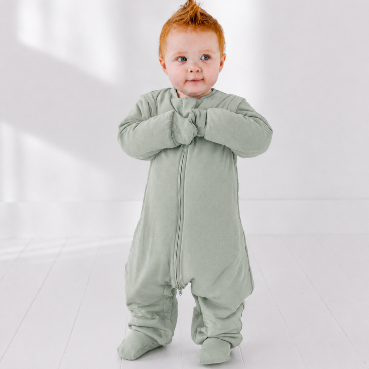 Baby wearing a light green onesie on a white background