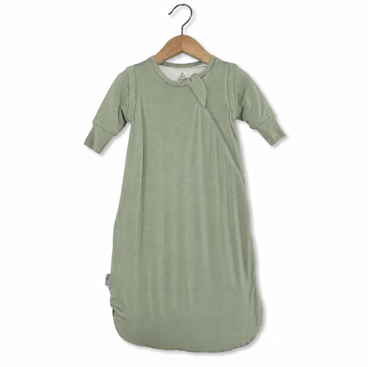 Green baby swaddle on a wooden hanger against a white background