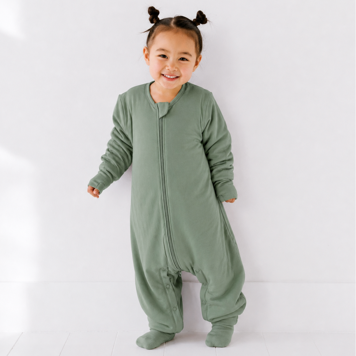 Child wearing a green onesie against a white background