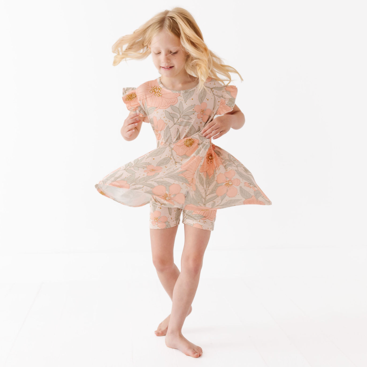 Young girl in a floral dress and shorts on a white background