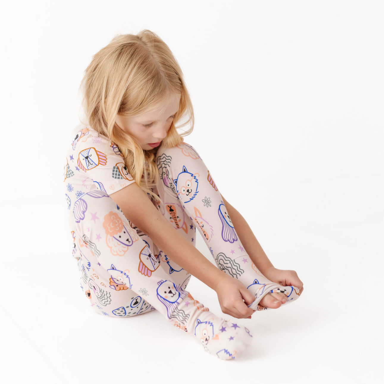 Child wearing pajama pants with colorful patterns on a white background