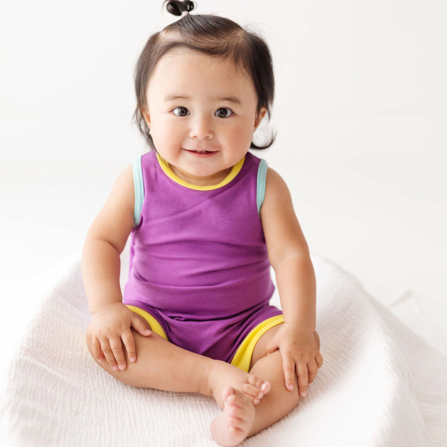 Child wearing a purple outfit with yellow trim on a white background