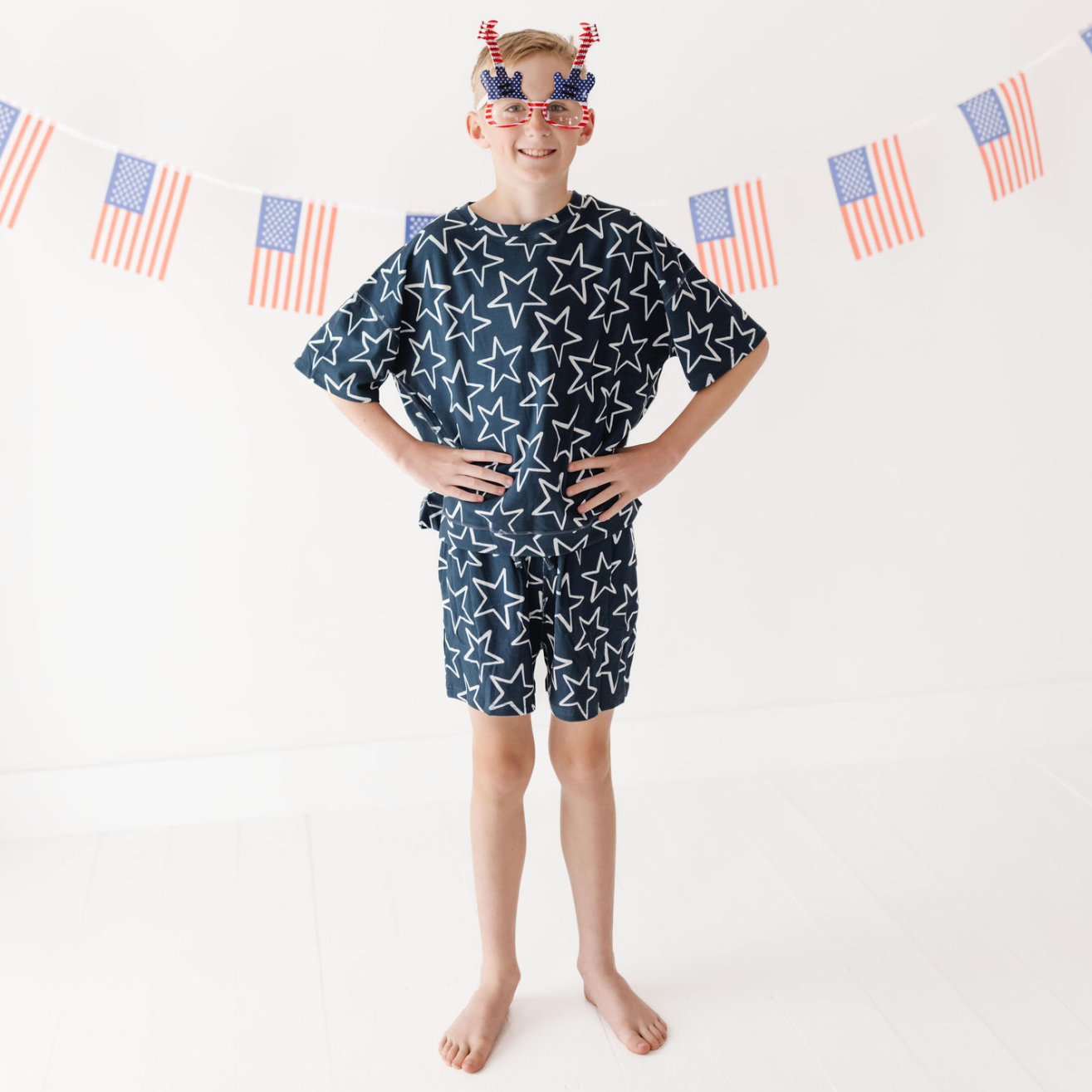 Child wearing a navy blue outfit with white star pattern in front of American flag decorations.