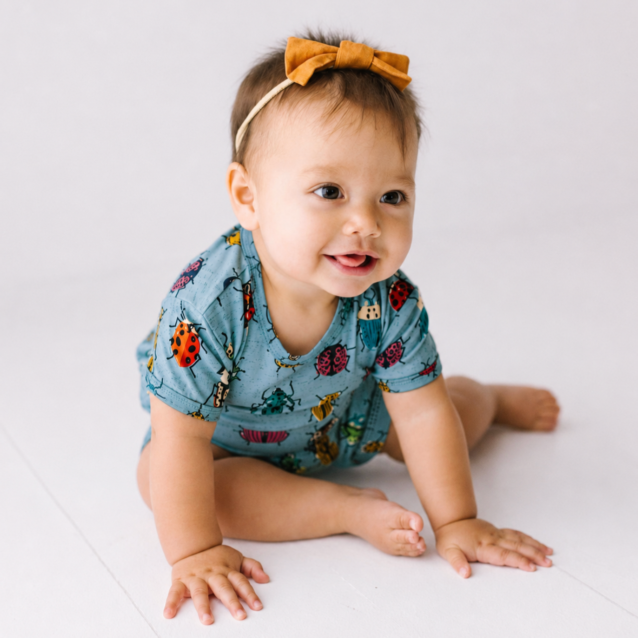 Baby wearing a blue romper with animal prints on a white background